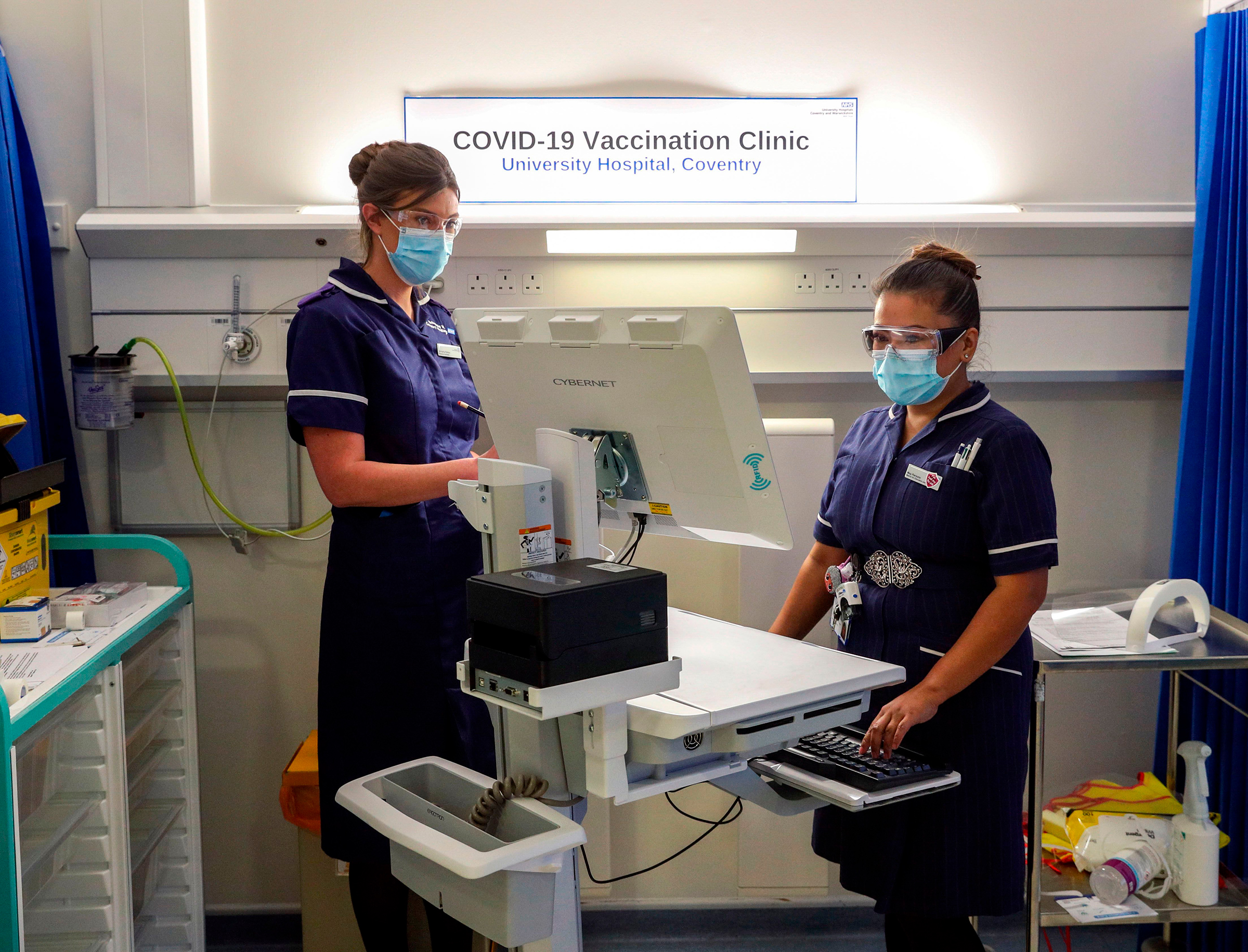 Wearing protective face coverings to combat the spread of the coronavirus, Matron May Parsons (R) is assessed by Victoria Parker (L) during training in the Covid-19 Vaccination Clinic at the University Hospital in Coventry, central England on December 4,