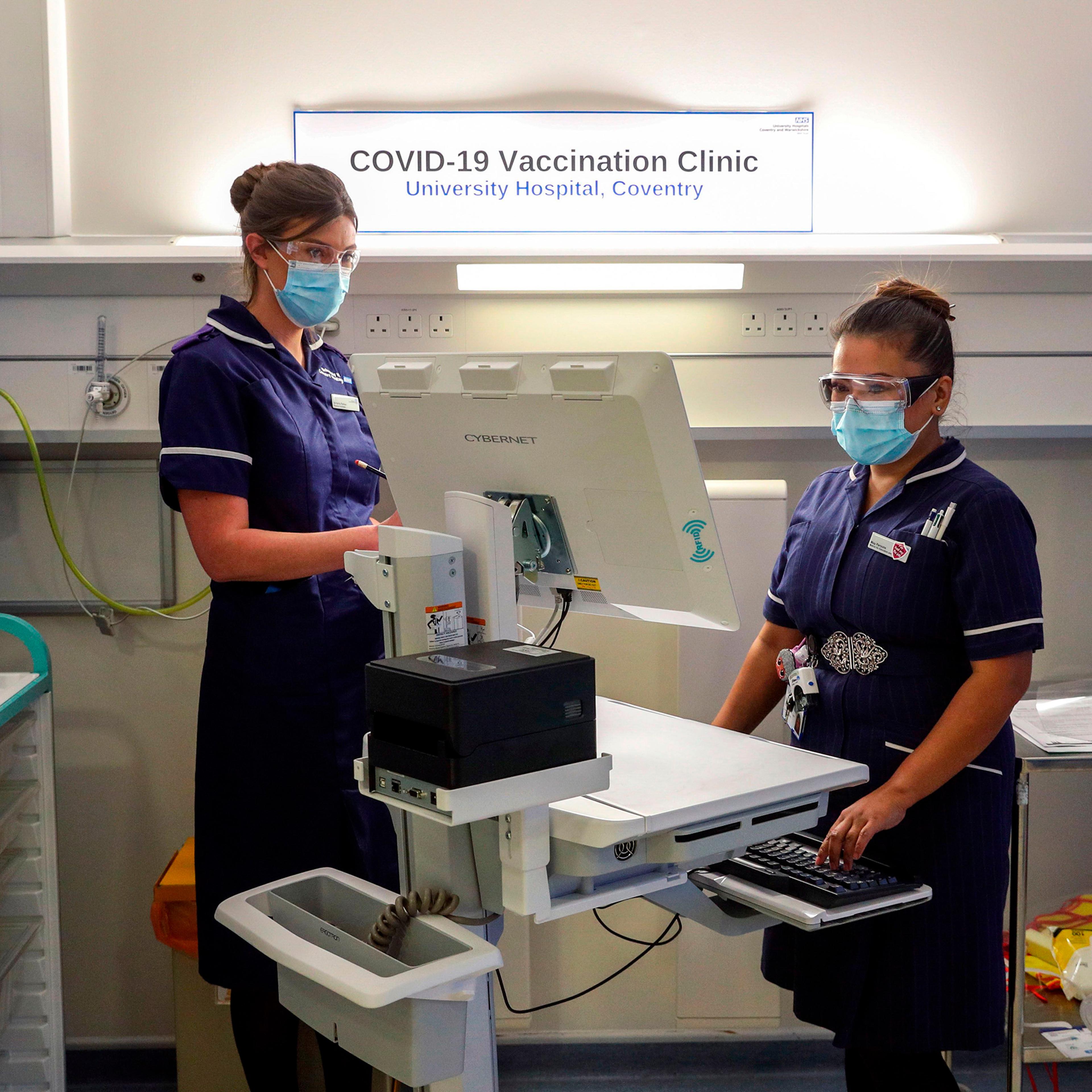 Wearing protective face coverings to combat the spread of the coronavirus, Matron May Parsons (R) is assessed by Victoria Parker (L) during training in the Covid-19 Vaccination Clinic at the University Hospital in Coventry, central England on December 4,
