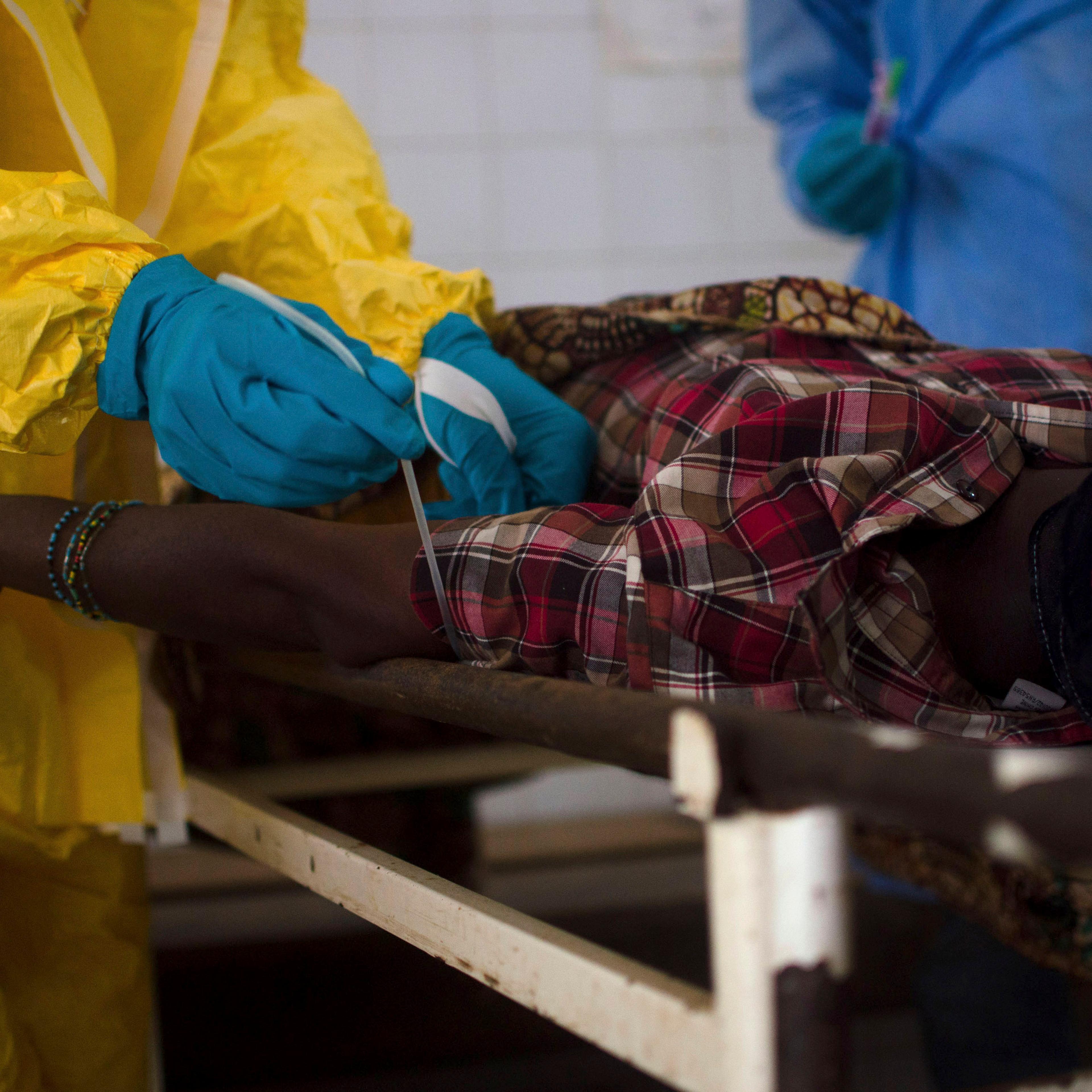 Medical staff take a blood sample from a suspected Ebola patient at the government hospital in Kenema