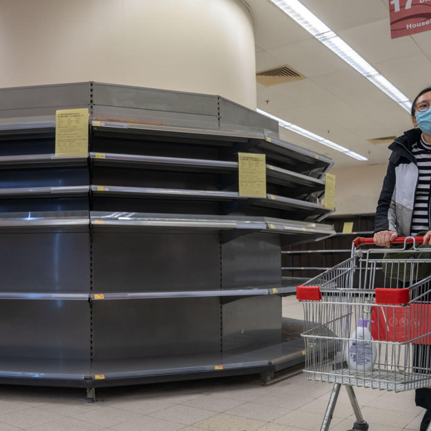A female shopper wearing a surgical mask walks past empty