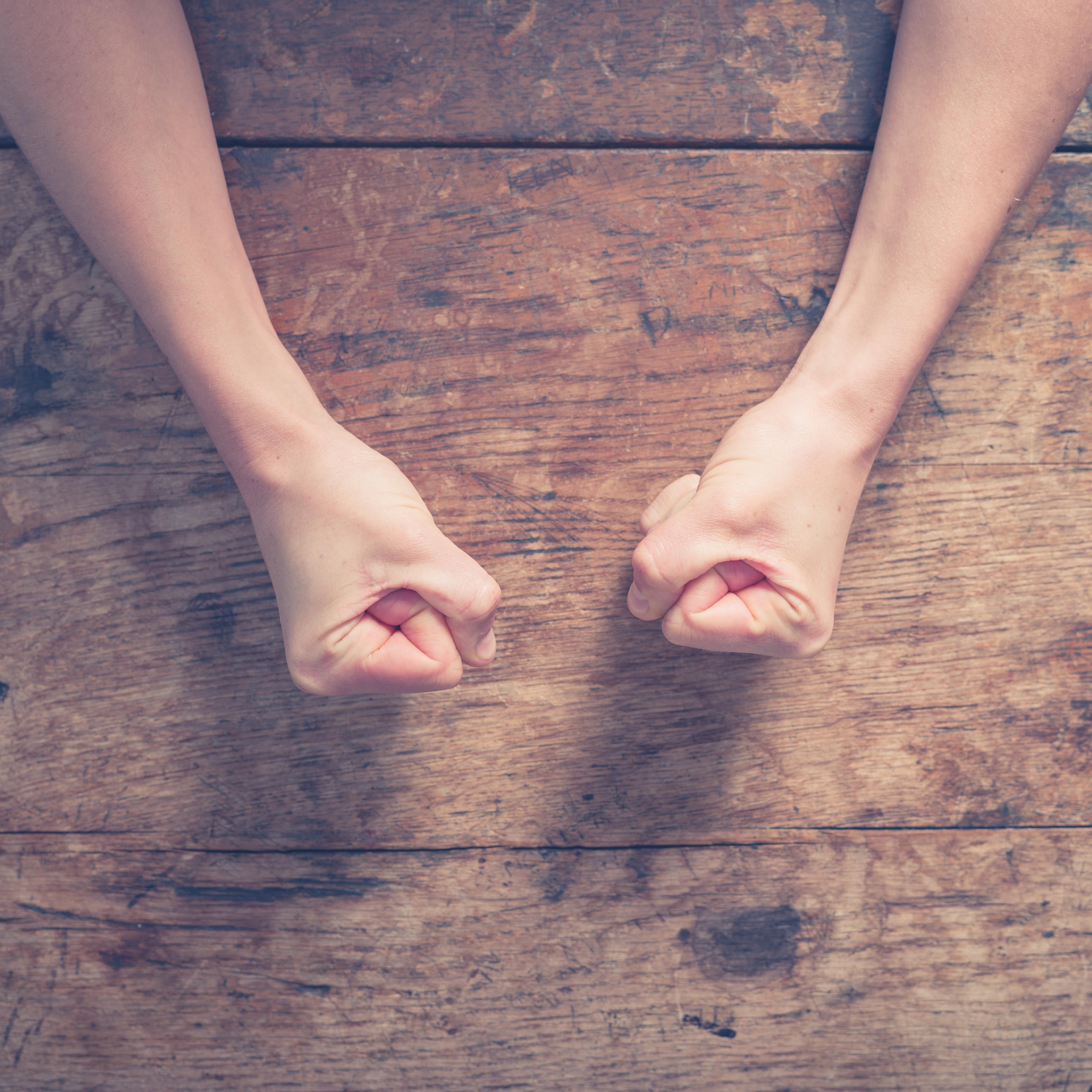 Female fists on a wooden table