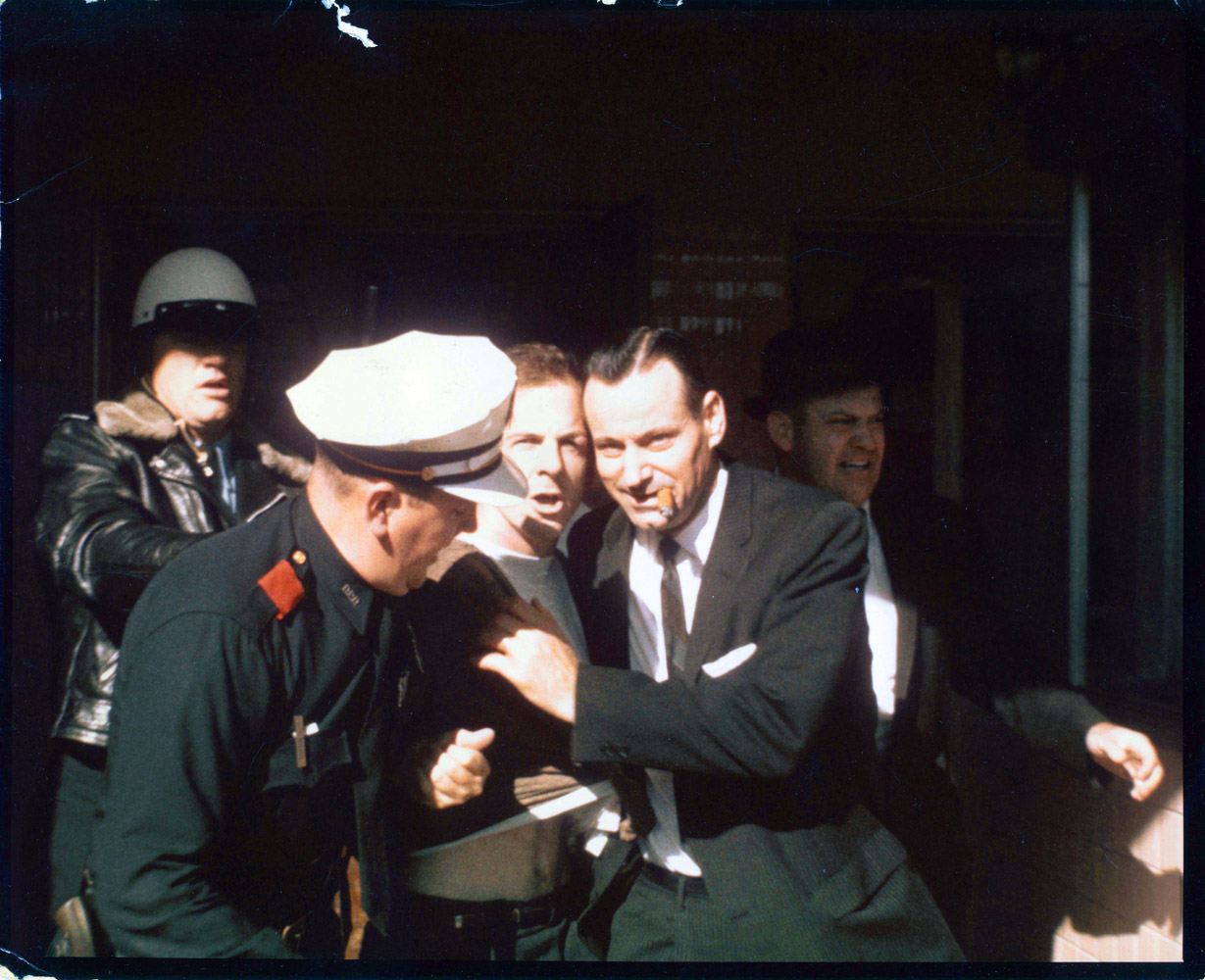 Lee Harvey Oswald is dragged from the Texas Theatre by Patrolman C.T. Walker and, still chewing his cigar, Detective Paul Bentley, on Nov. 22, 1963. On the right right is Sgt. Gerald Hill.