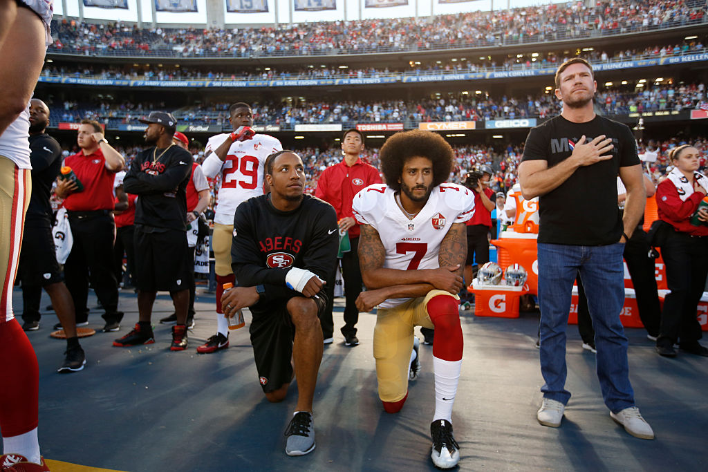 Eric Reid #35 and Colin Kaepernick #7 of the San Francisco 49ers kneel on the sideline during the anthem, as free agent Nate Boyer stands, prior to the game against the San Diego Chargers at Qualcomm Stadium in San Diego, Calif., on Sept. 1, 2016.