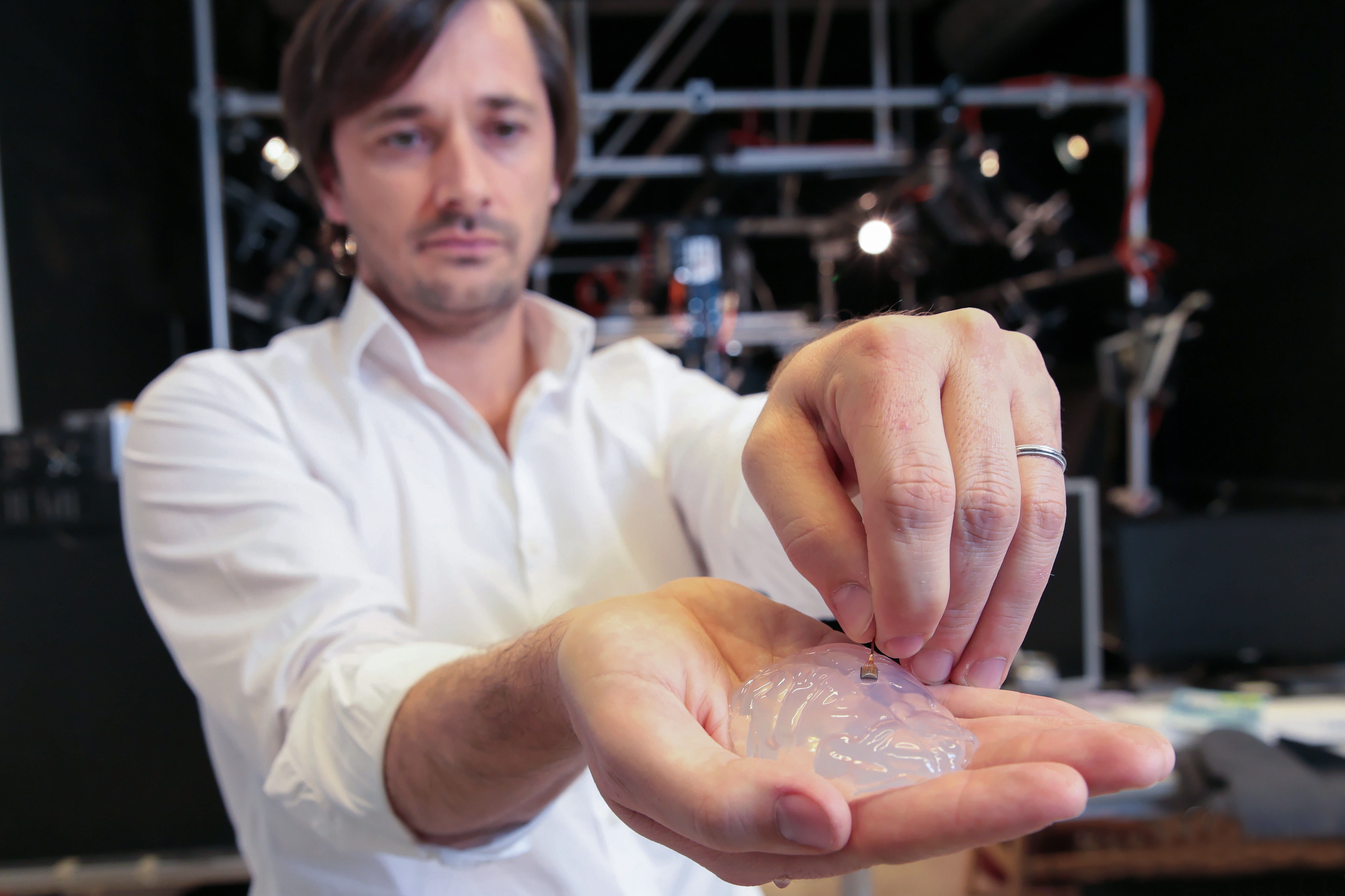 Grégoire Courtine holds a silicon model of a primate’s brain and a brain implant. The brain-spine interface uses a microelectrode array like this one to detect spiking activity of the brain’s motor cortex