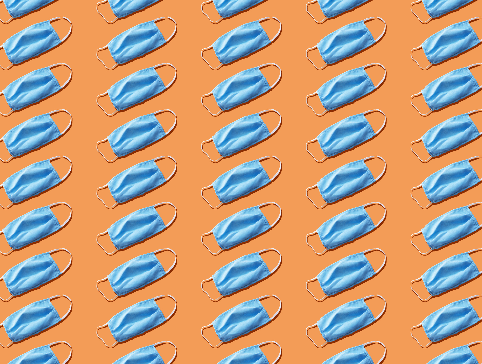 Blue medical face mask to avoid contagious diseases pattern on orange background