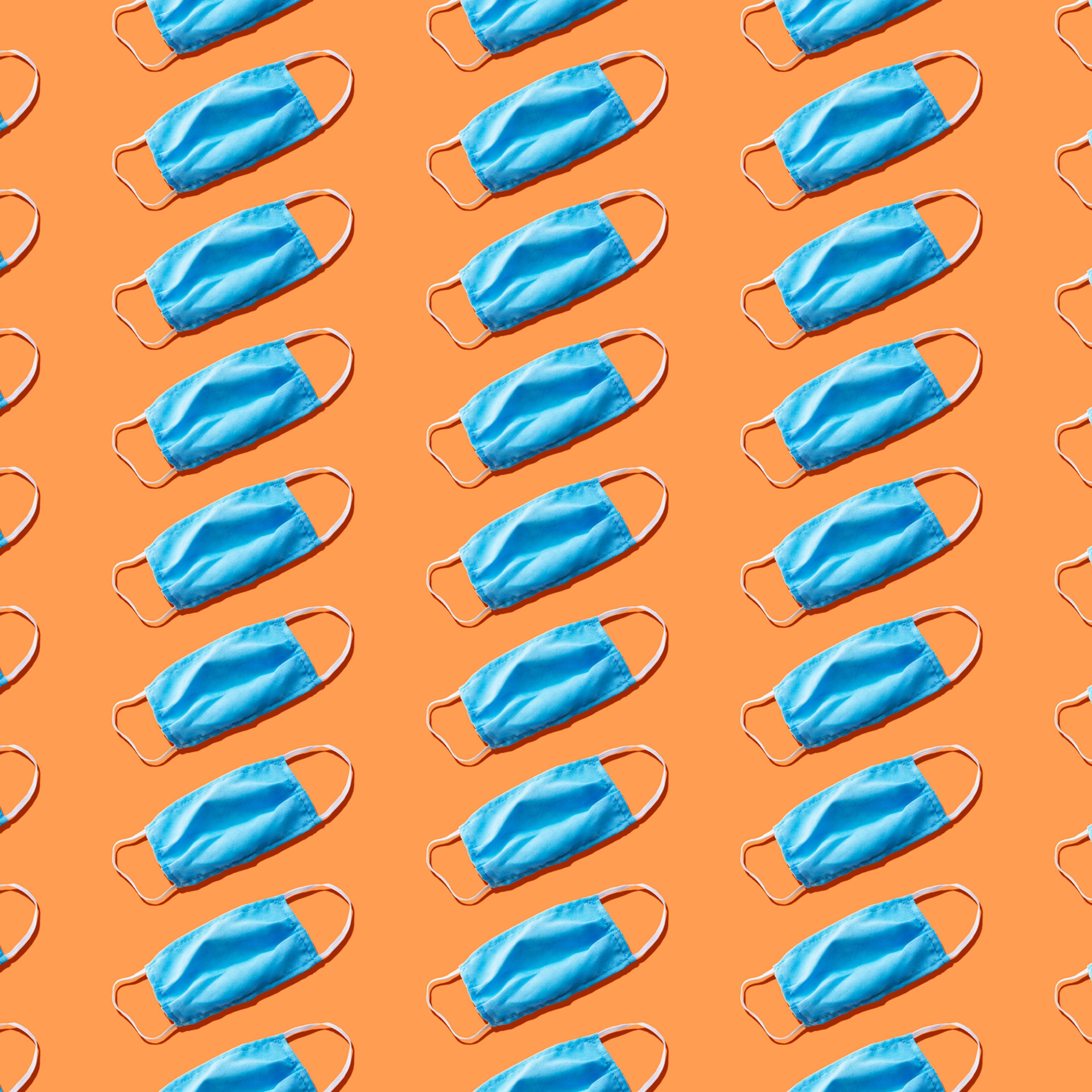 Blue medical face mask to avoid contagious diseases pattern on orange background