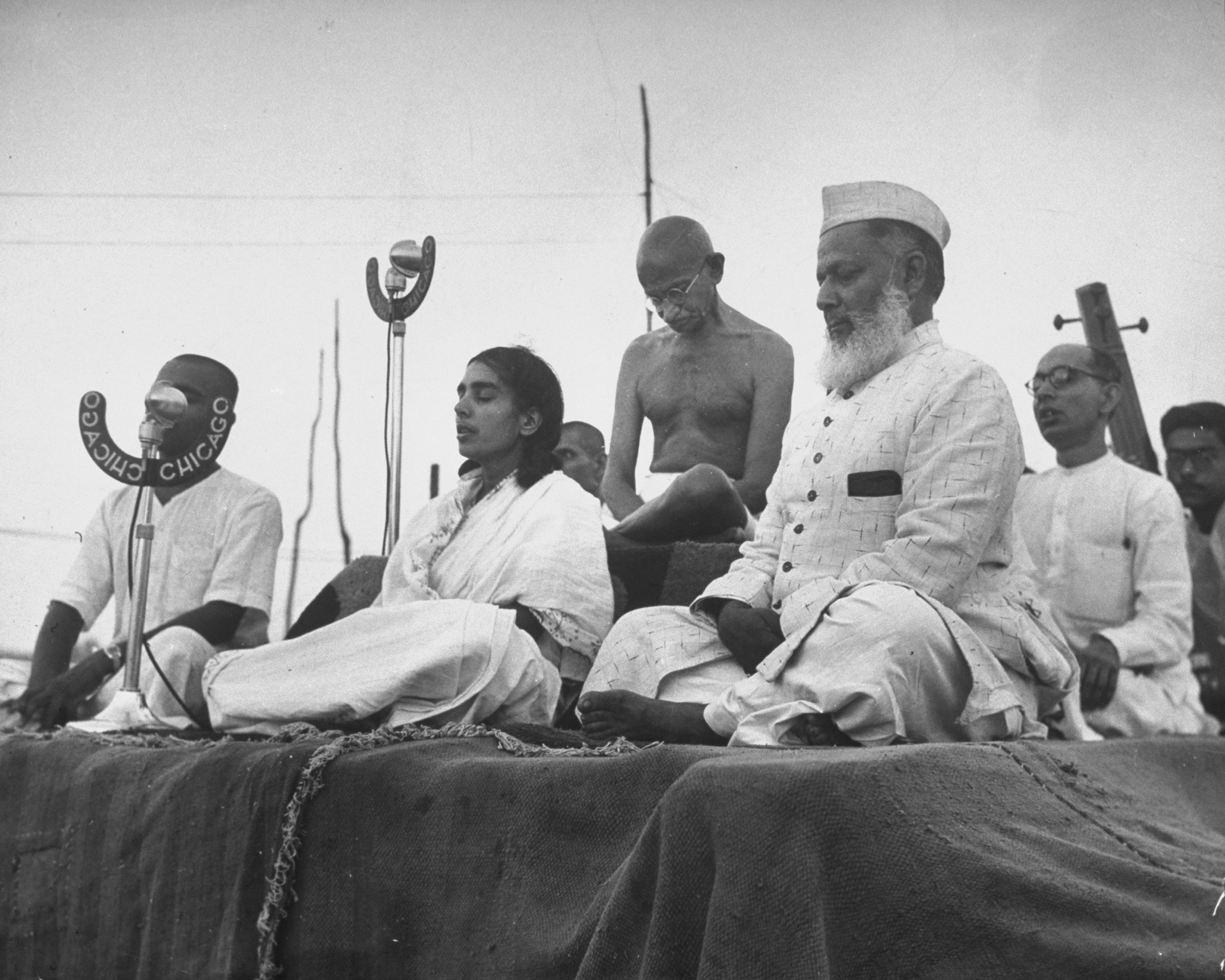 Gandhi joins, from the left, his nephew Kanu (behind the microphone), secretary Sushila Pai, Anis Ahmed, and secretary Pyarelal for a prayer meeting in 1946.