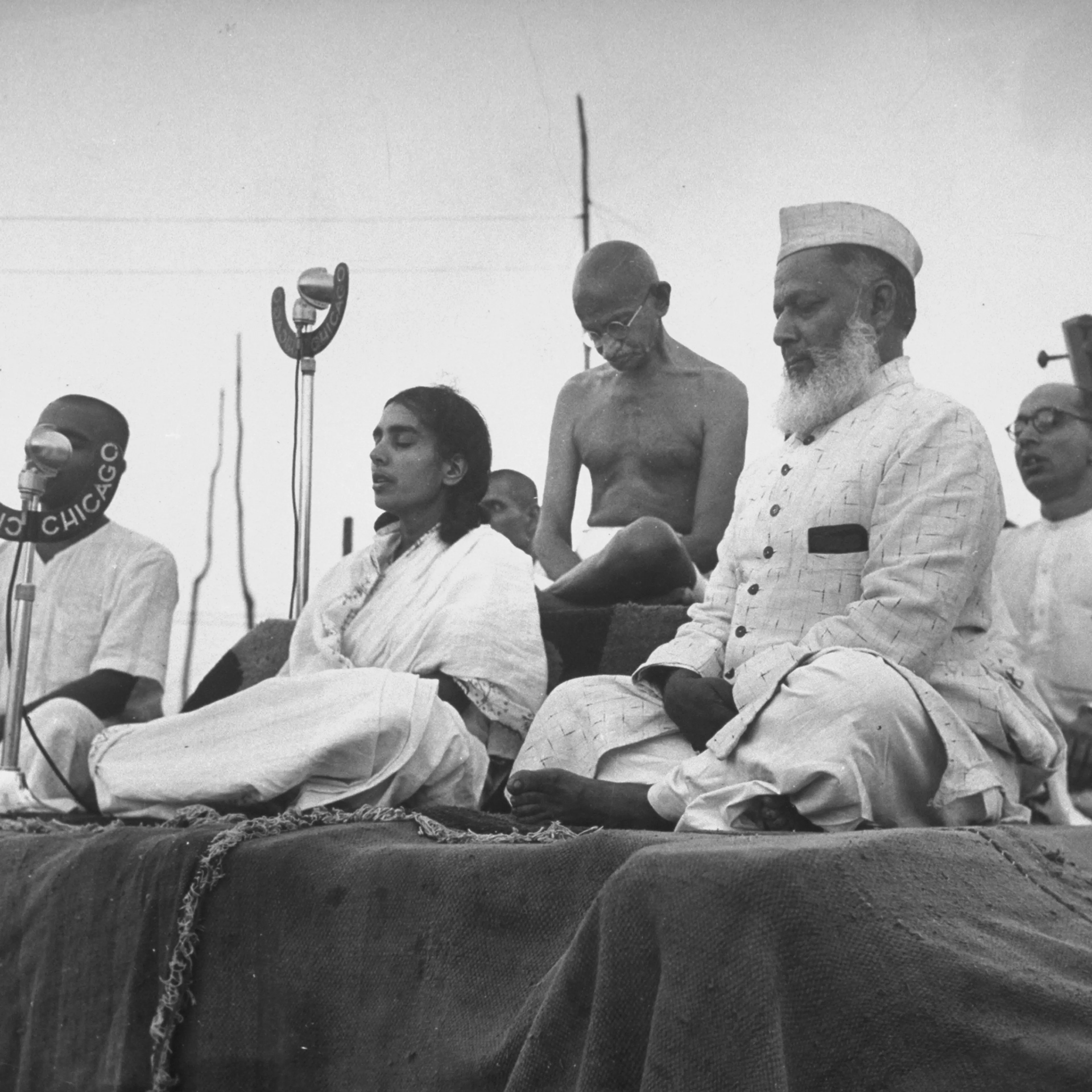 Gandhi joins, from the left, his nephew Kanu (behind the microphone), secretary Sushila Pai, Anis Ahmed, and secretary Pyarelal for a prayer meeting in 1946.