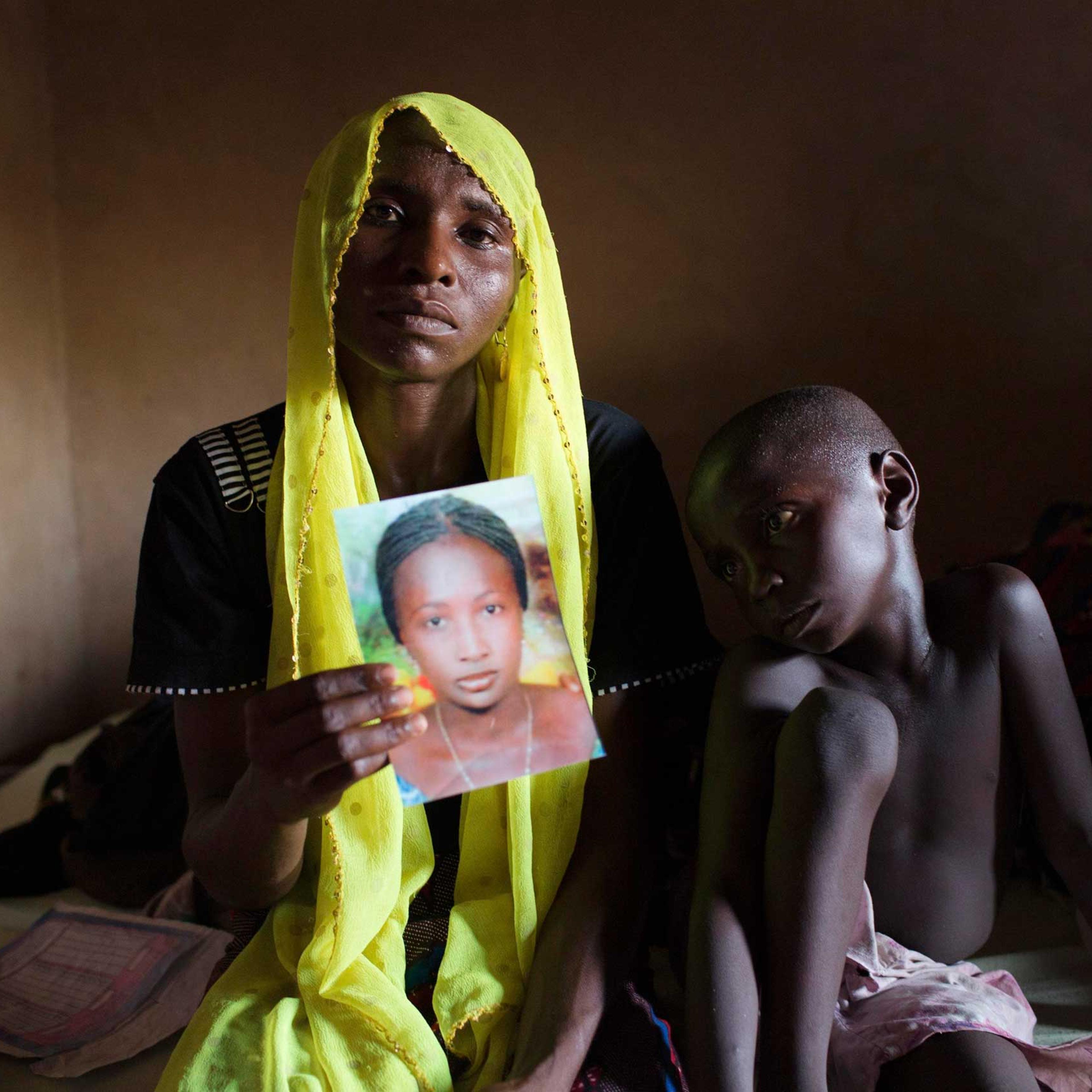 File photo shows Rachel Daniel holding up a picture of her abducted daughter Rose Daniel as her son Bukar sits beside her at her home in Maiduguri