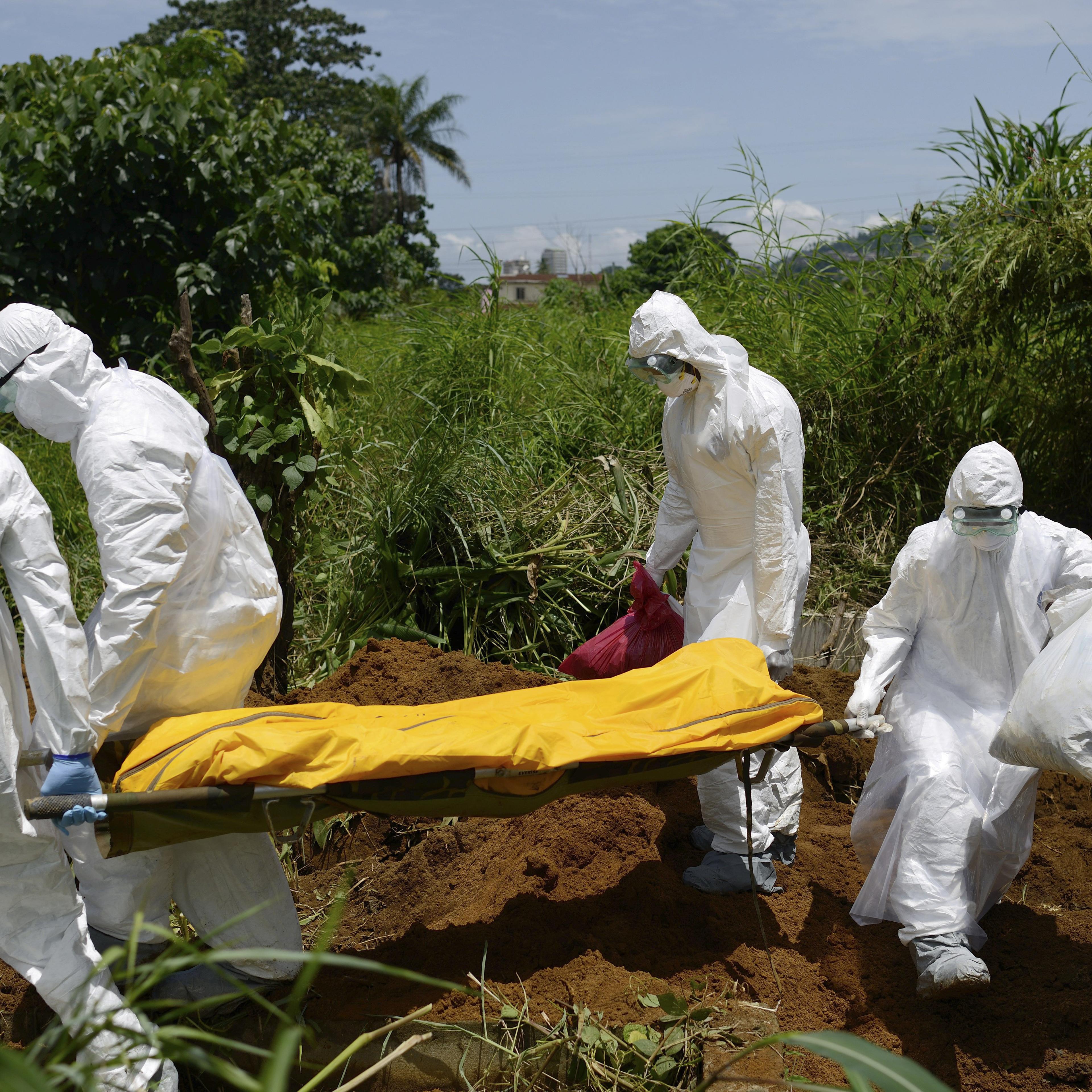 Members of a burial team wearing protective suits bury an Ebola victim in Freetown, Sierra Leone.