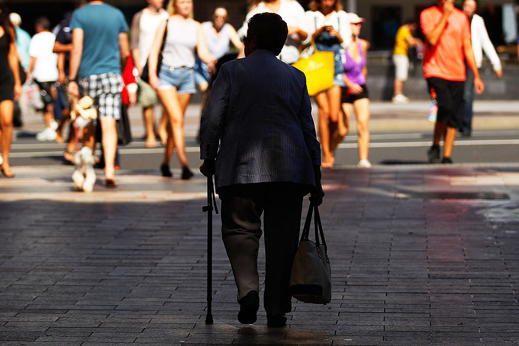 A woman holding a walking cane walks along a street in Sydney, Australia, on Wednesday, April 1, 2015.