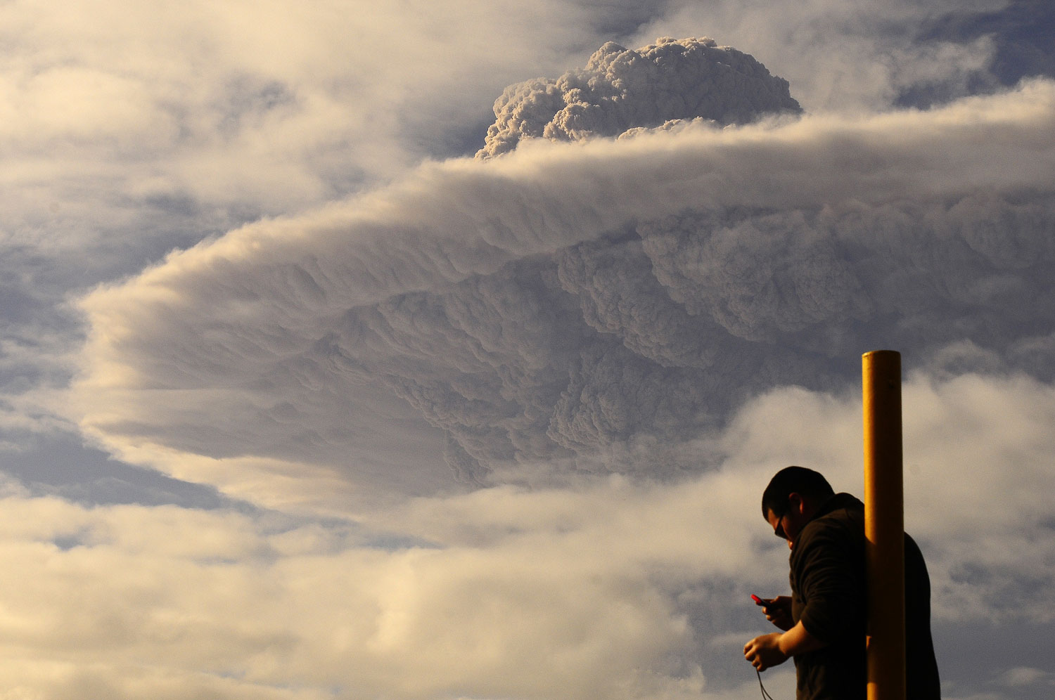 A tourist watches the cloud of ash billowing from Puyehue volcano at a town in southern Chile, June 5, 2011.