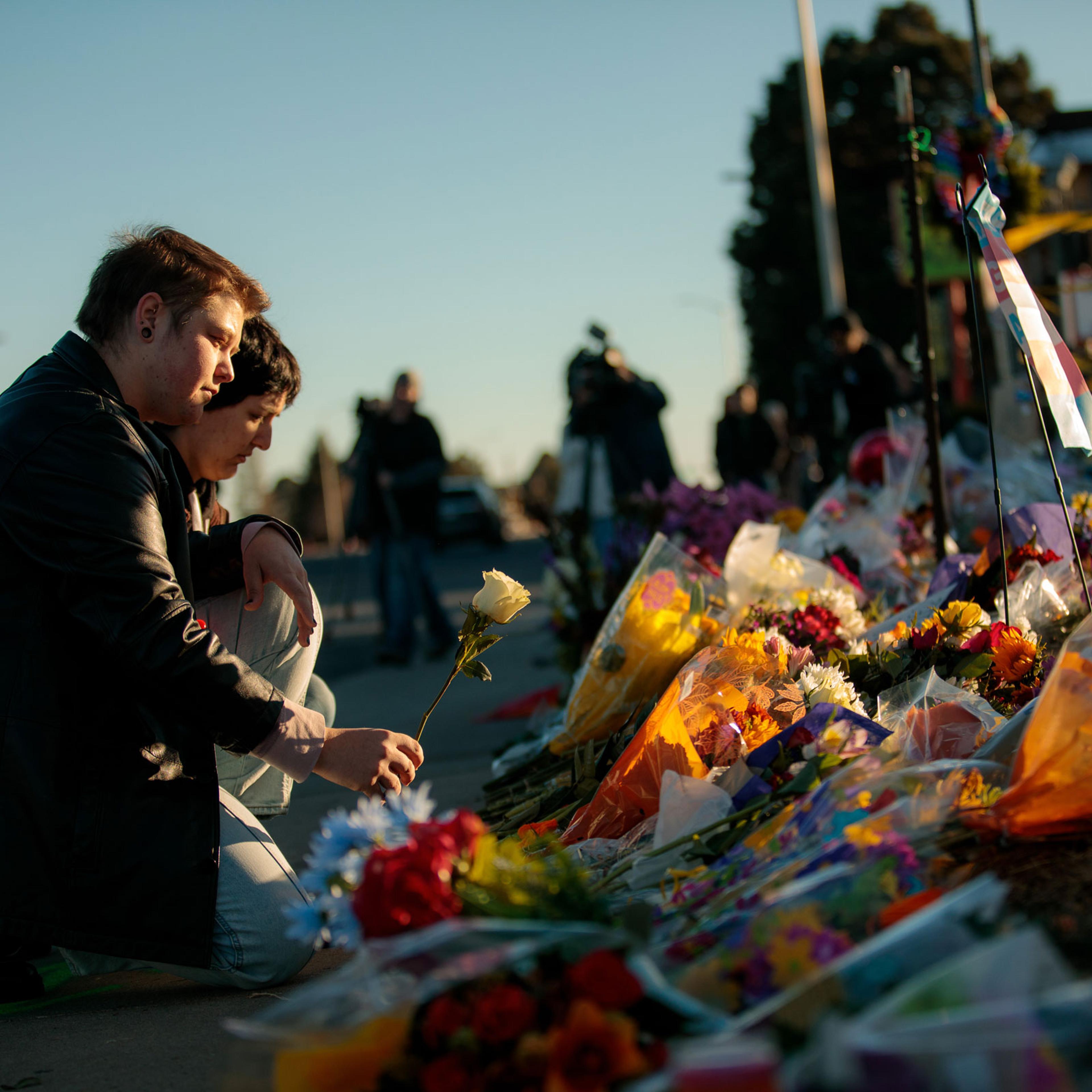 Ren Kurgis, left, and Jessie Pacheco leave flowers at the growing memorial near the scene of the shooting inside Club Q in Colorado Springs, Colo., on Sunday, Nov. 20, 2022.