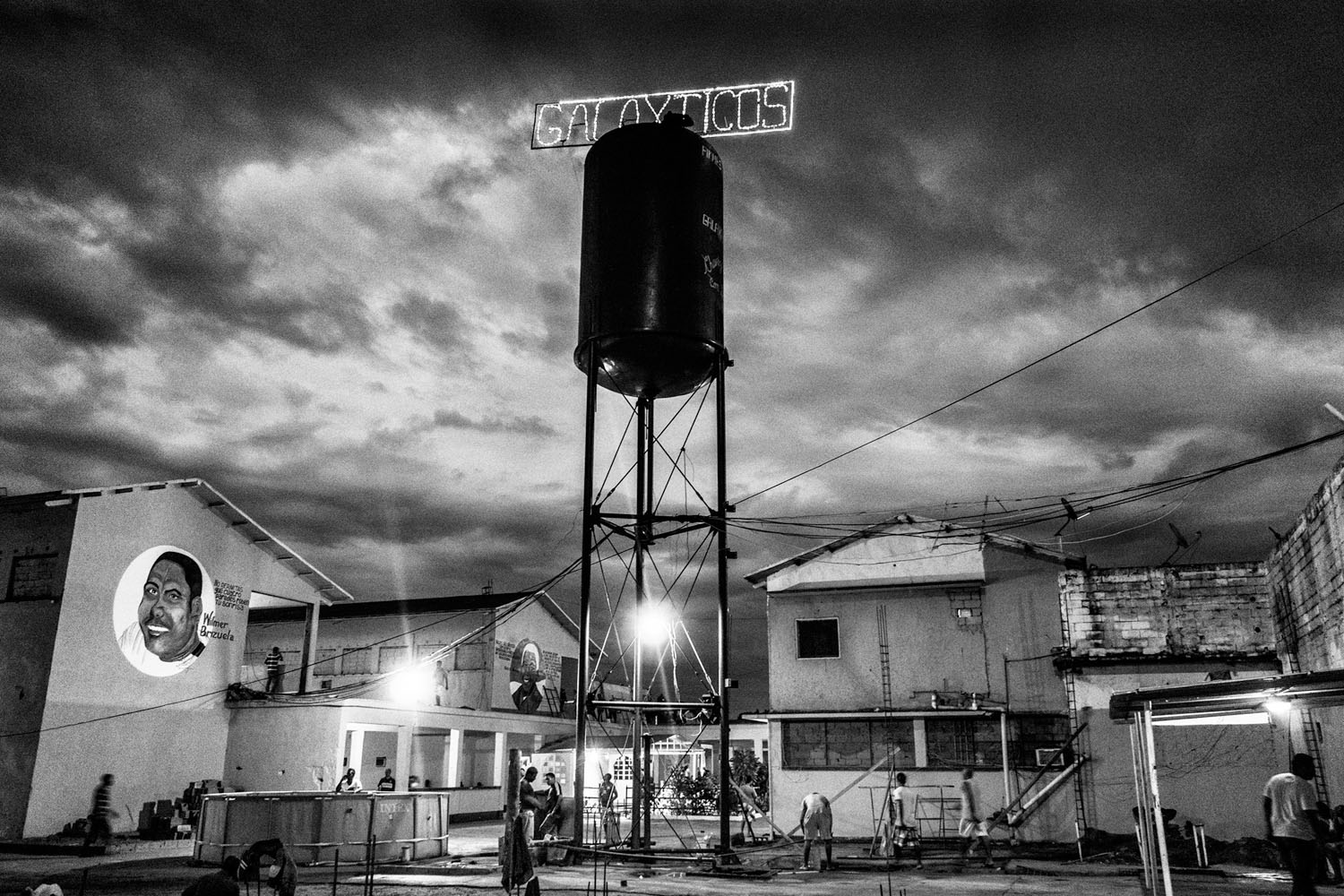 CIUDAD BOLIVAR, VENEZUELA - APRIL 2013: General vision of Vistahermosa Prison. An elevated water tank with the name of the carro "Galaxticos" illuminates the jail overnight and reminds all who are in charge. In the left, a mural with the chief of the pri