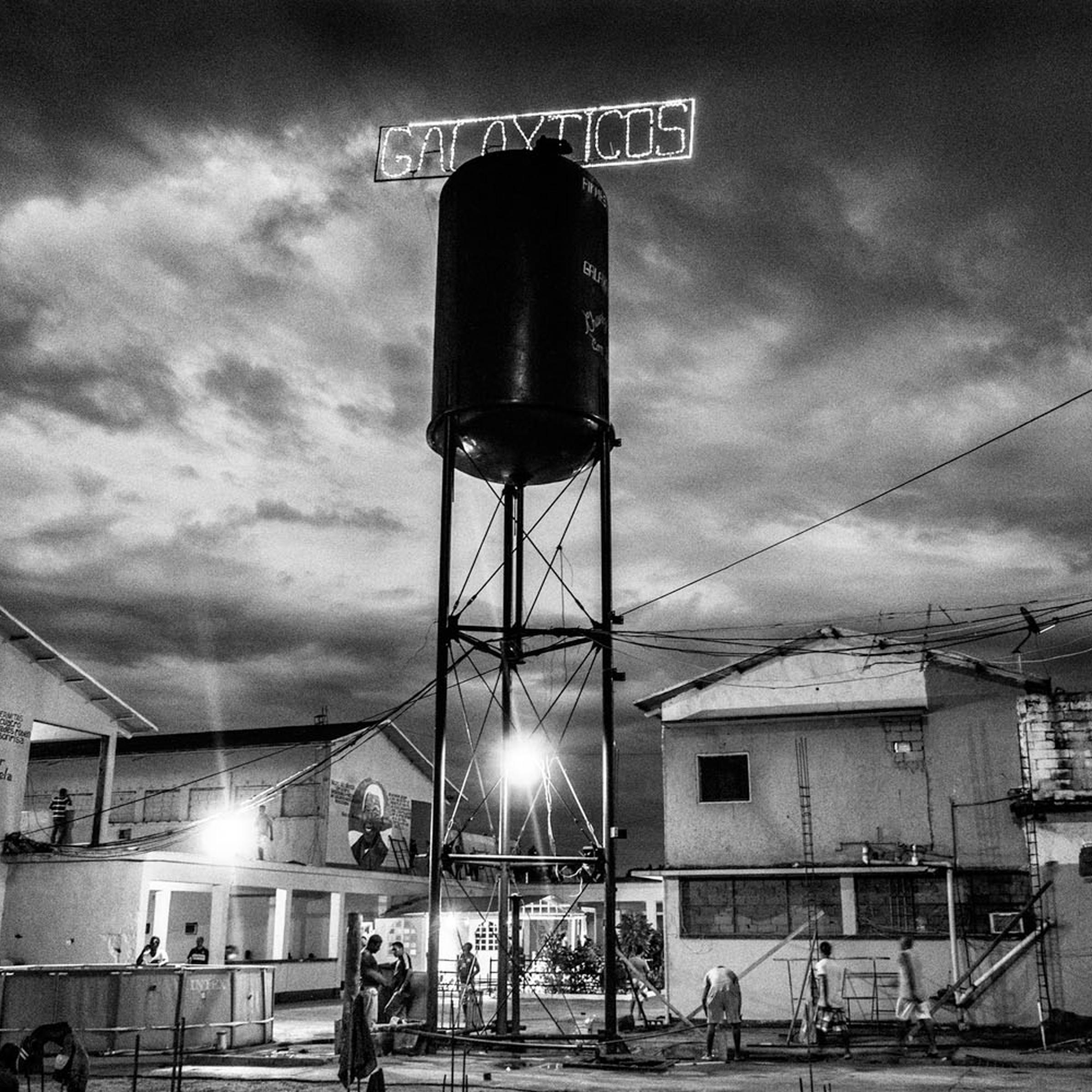 CIUDAD BOLIVAR, VENEZUELA - APRIL 2013: General vision of Vistahermosa Prison. An elevated water tank with the name of the carro "Galaxticos" illuminates the jail overnight and reminds all who are in charge. In the left, a mural with the chief of the pri