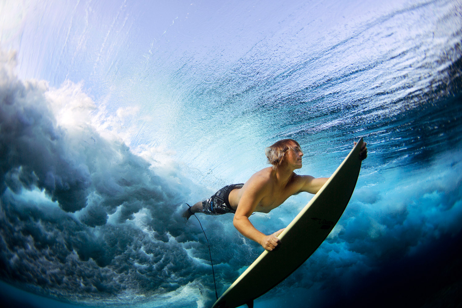 Surfer Stu Johnson duck dives his board to clear the rolling waves of the ocean at Cloudbreak, an outer reef in Fiji.