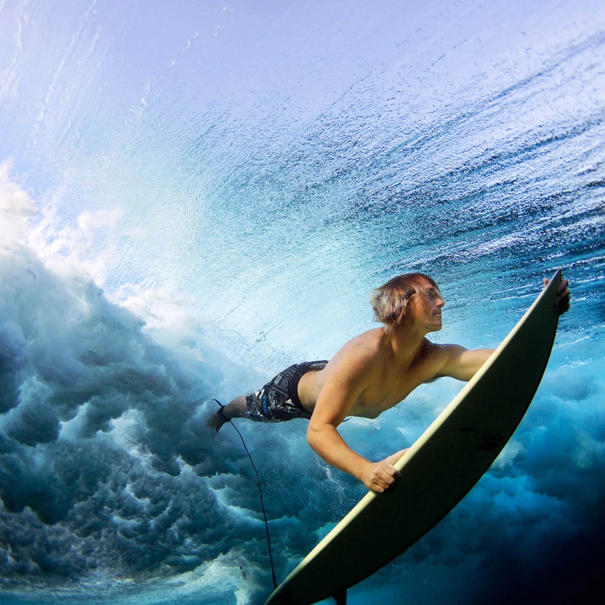 Surfer Stu Johnson duck dives his board to clear the rolling waves of the ocean at Cloudbreak, an outer reef in Fiji.