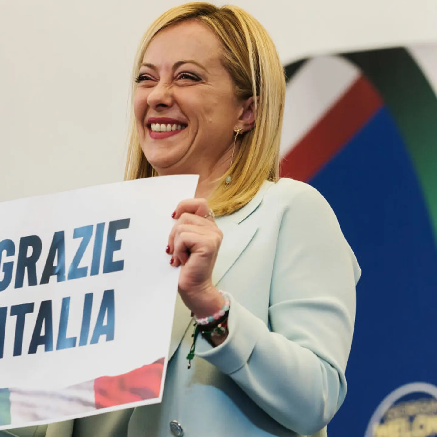Giorgia Meloni is seen holding a placard quoting "Thanks