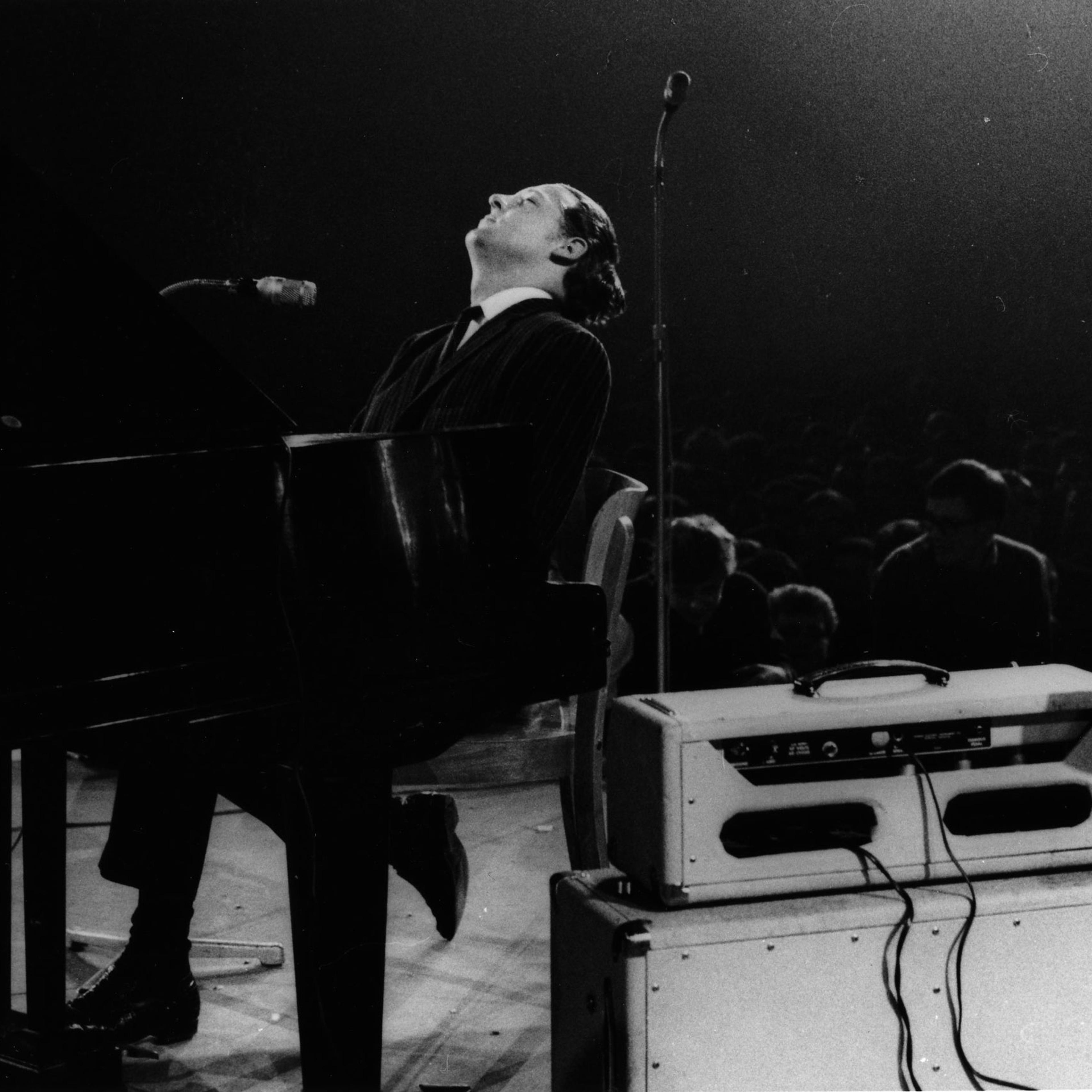 Jerry Lee Lewis performs on stage, singing into two microphones, at the Deutschlandhalle in 1963 in Berlin.
