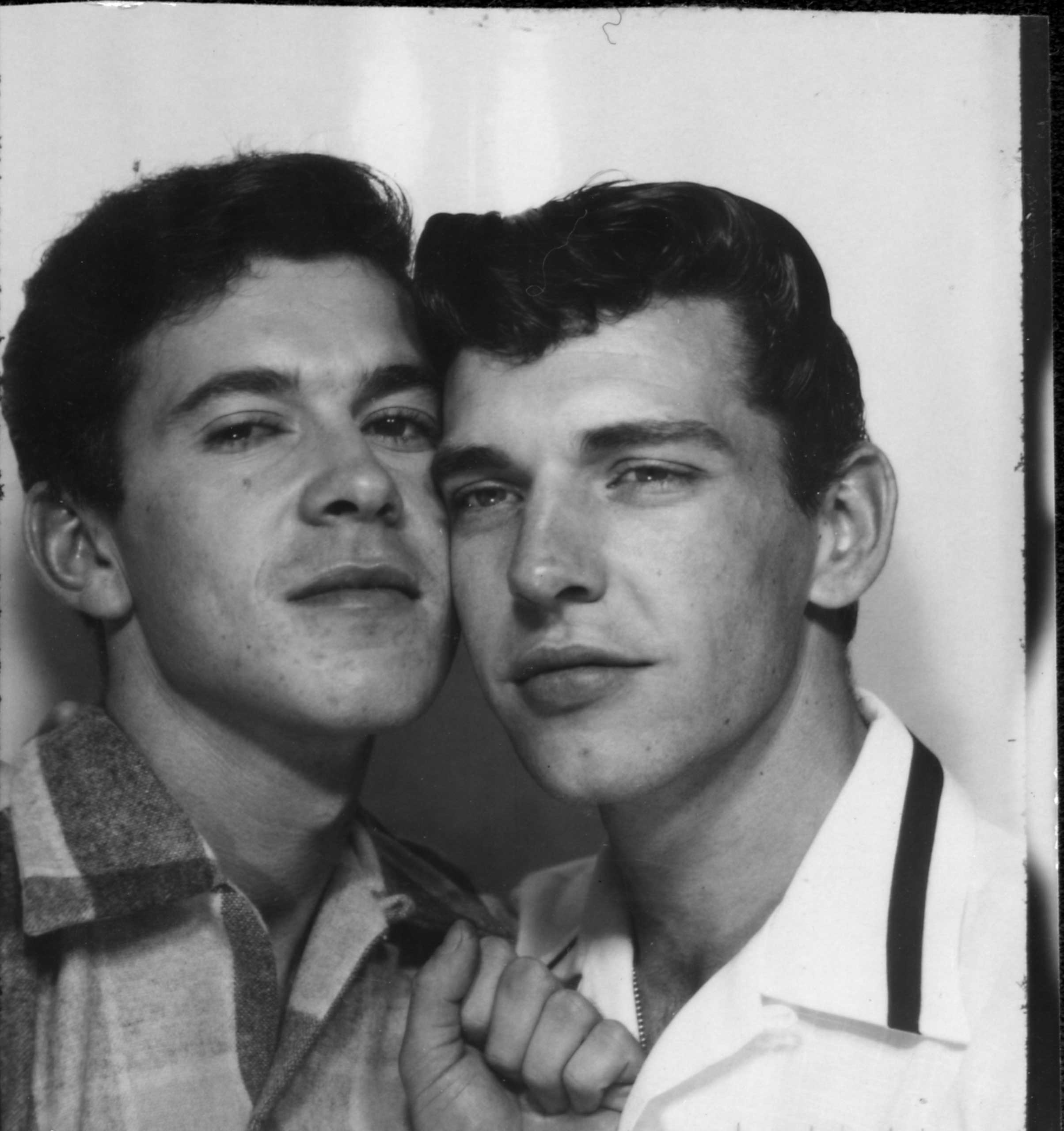 J. J. Belanger cheek-to-cheek with a man in a photo booth. "PGE exhibition, Hastings Park." Vancouver, Circa 1953.
