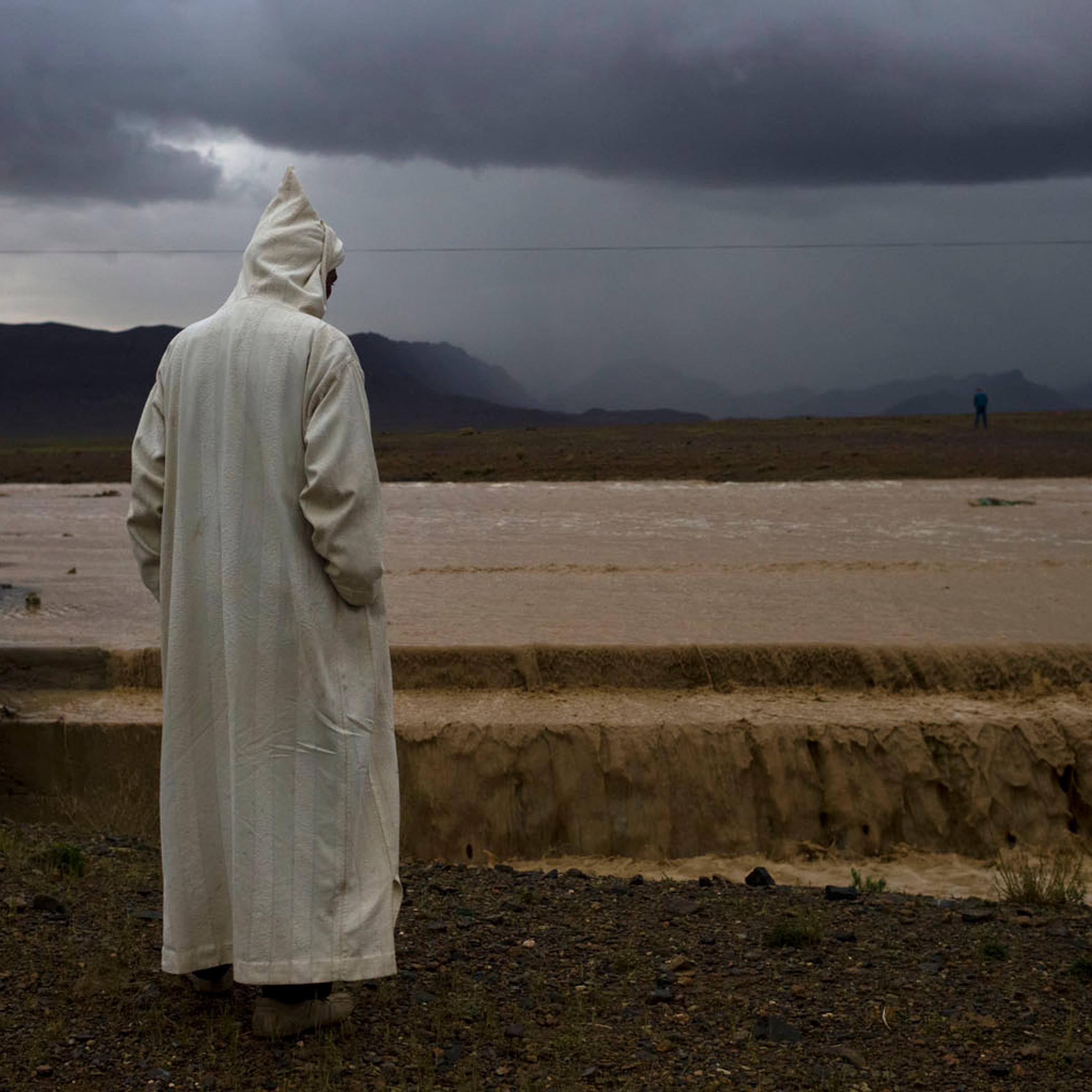 Morocco, 2011.
A passenger of a bus waits while a flash flood takes out the road ahead of them near the northern edge of the Sahara desert in present-day Morocco