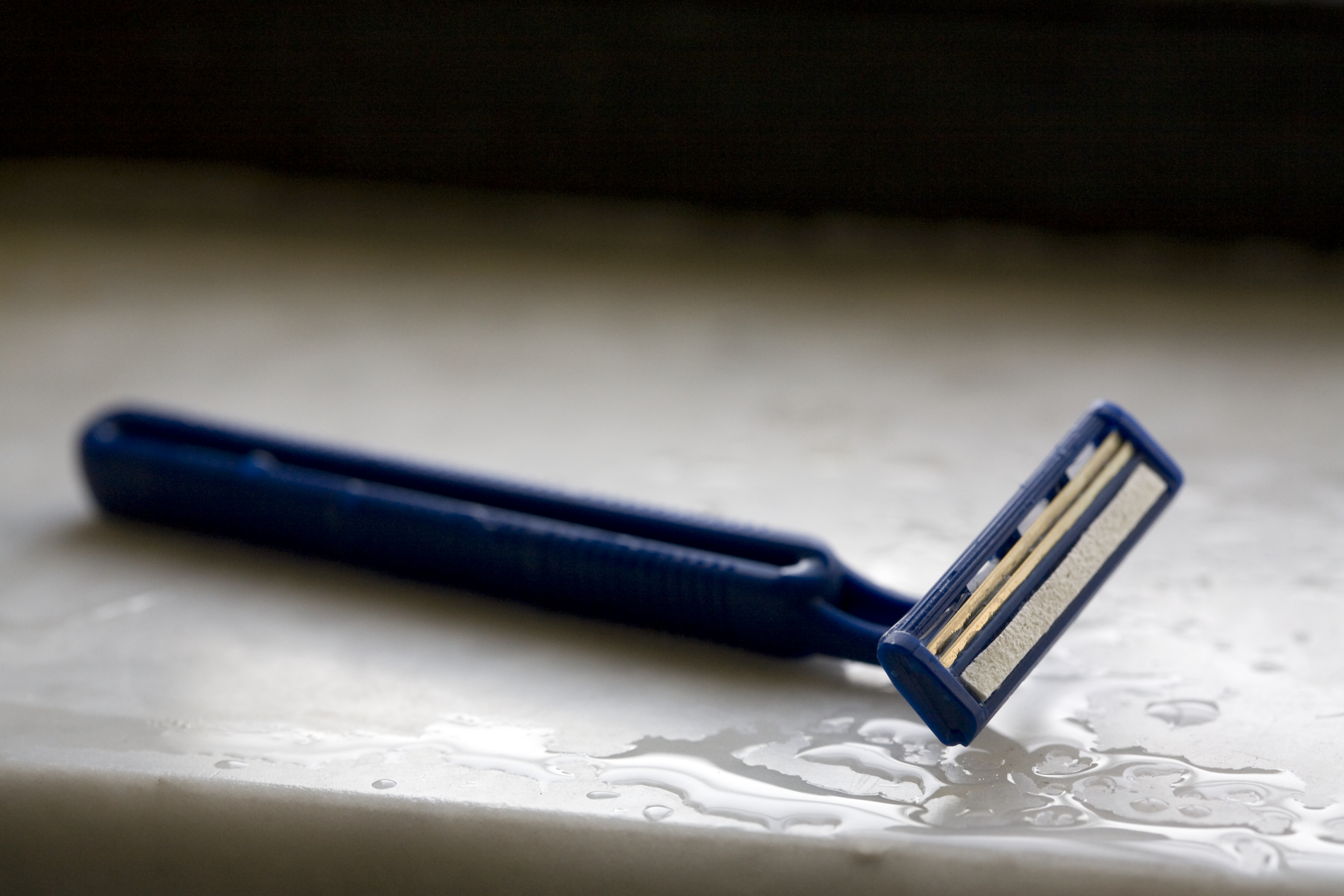 Disposable razor on wet surface, close-up