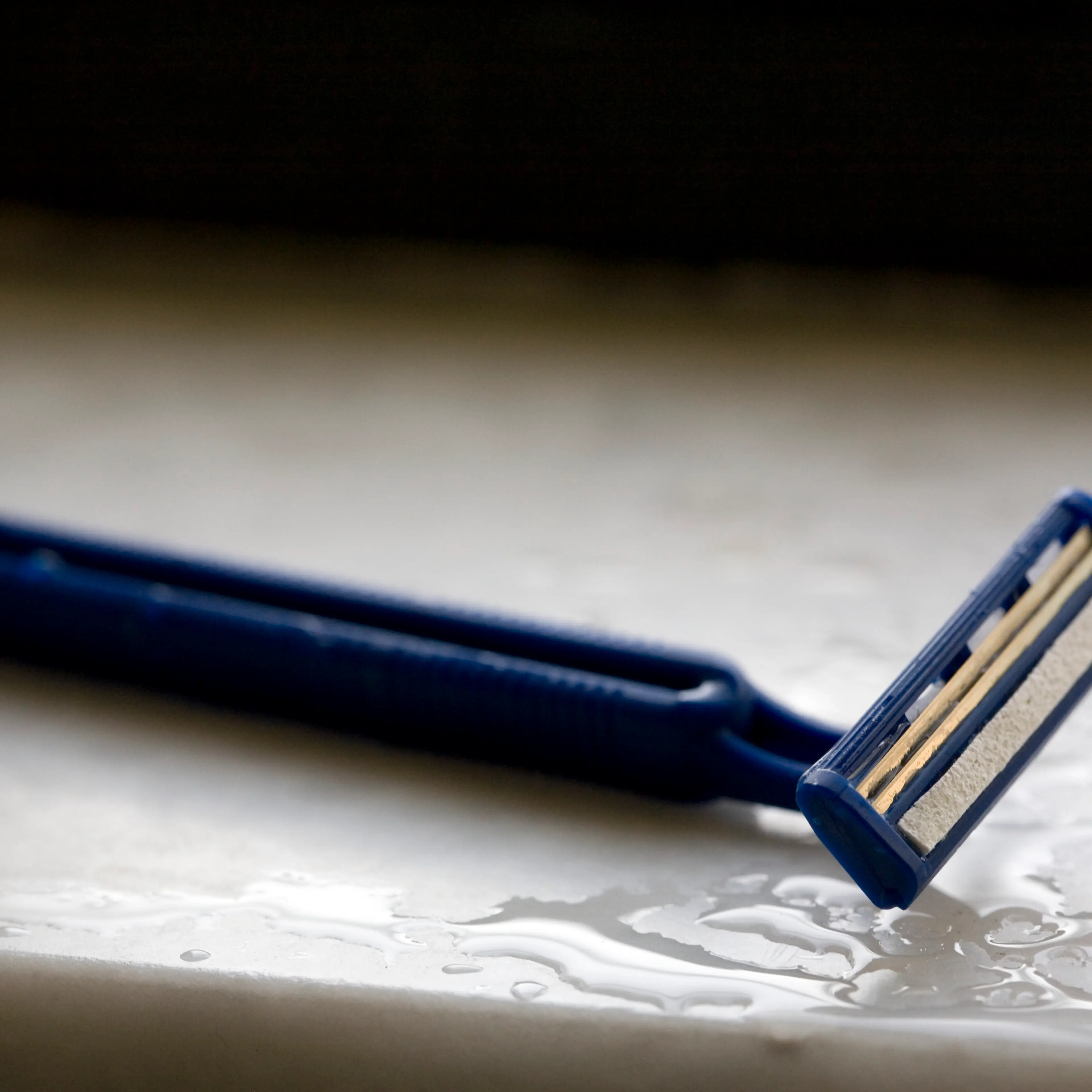 Disposable razor on wet surface, close-up