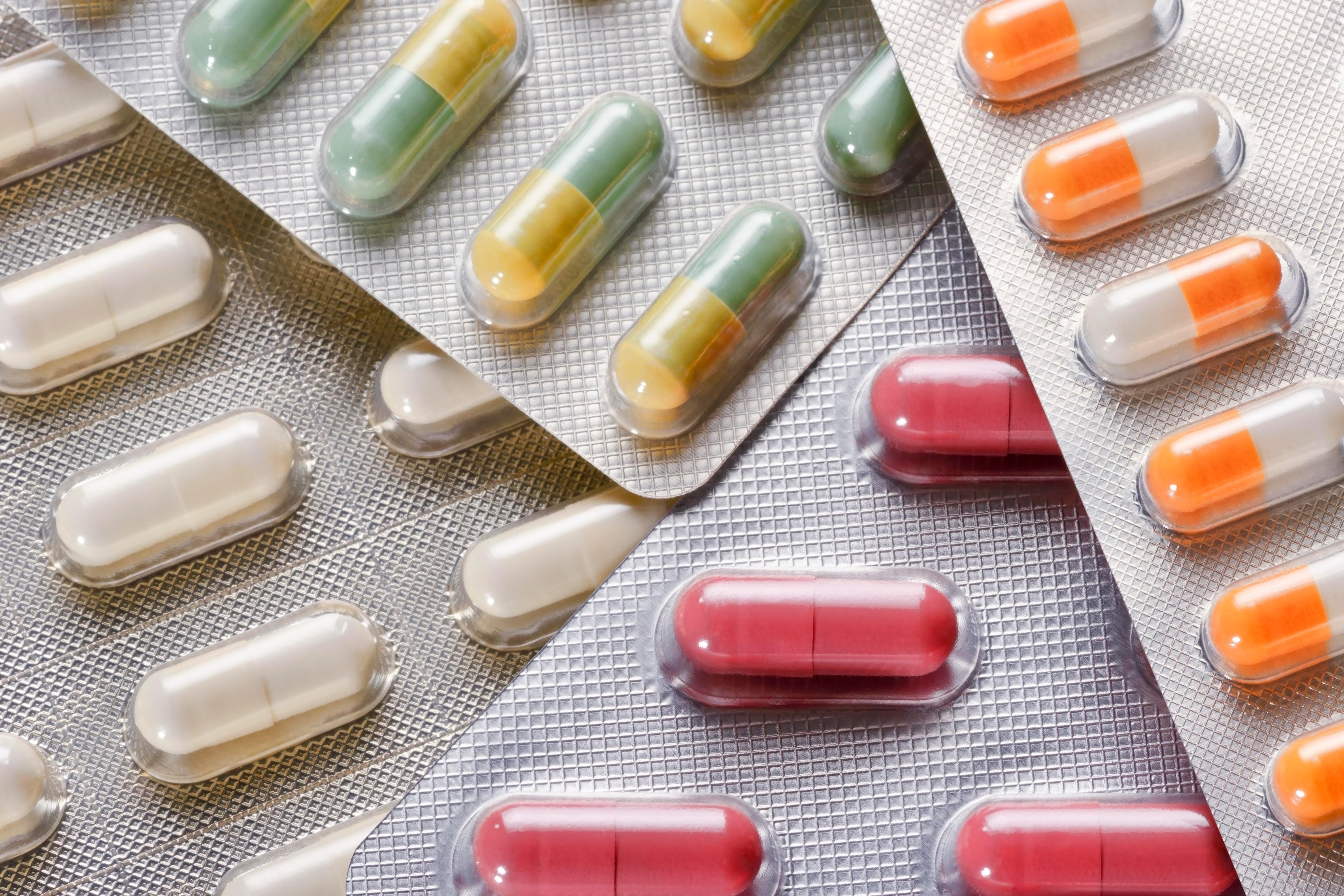 Various packs of pills of different colors placed on top of each other.