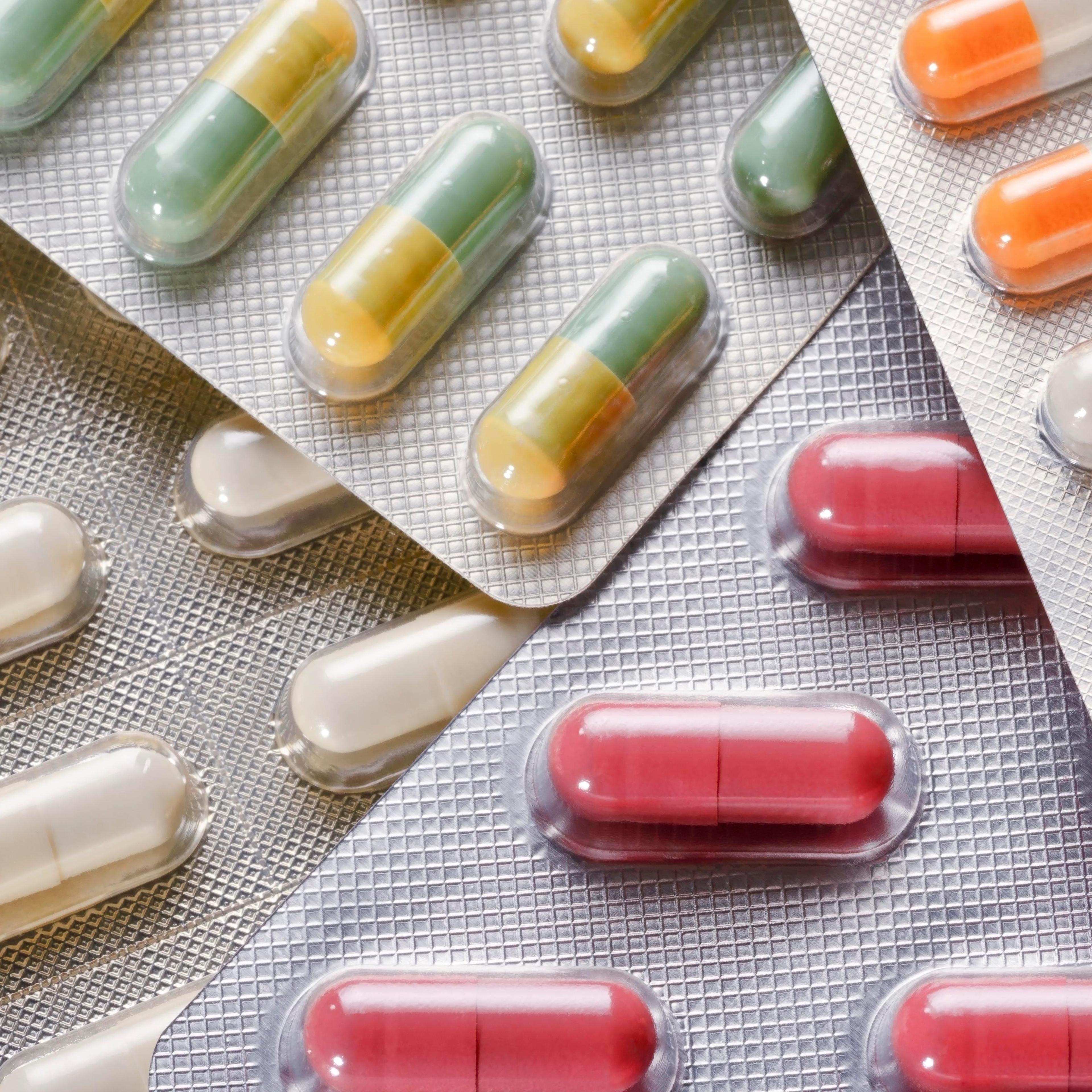 Various packs of pills of different colors placed on top of each other.