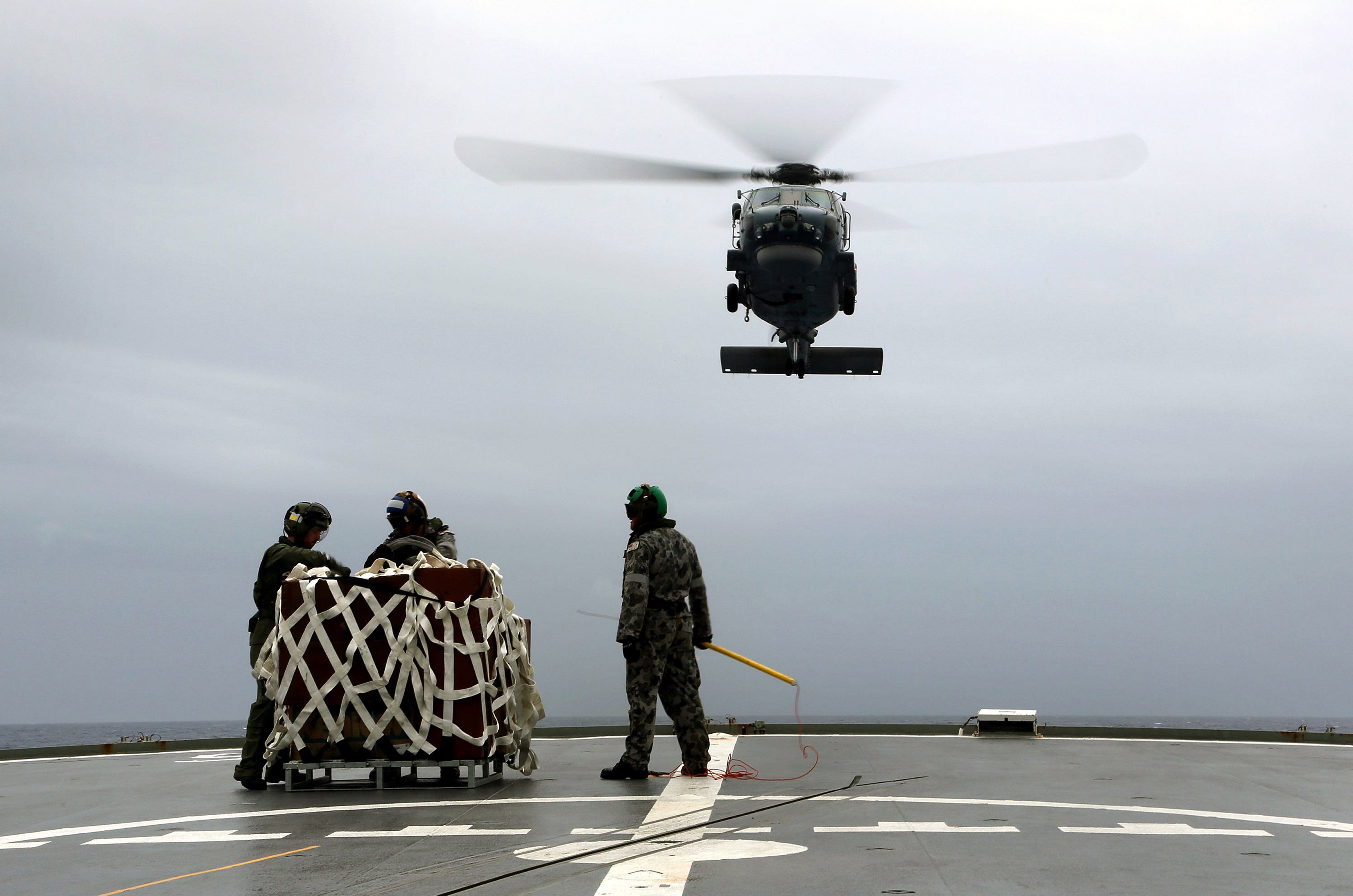 A S-70B-2 Seahawk (Tiger 75) helicopter approaches the flight deck of Australian Navy ship HMAS Toowoomba to pick up supplies during a vertical replenishment at sea with HMAS Success as they continue to search for the missing Malaysian Airlines flight MH