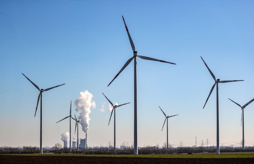 The chimney and cooling towers of the Schkopau lignite-fired power plant are steaming behind a wind farm in Germany.