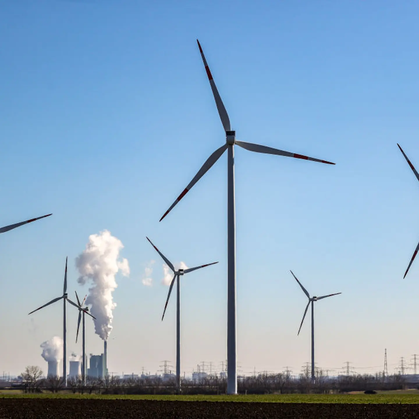 The chimney and cooling towers of the Schkopau lignite-fired power plant are steaming behind a wind farm in Germany.