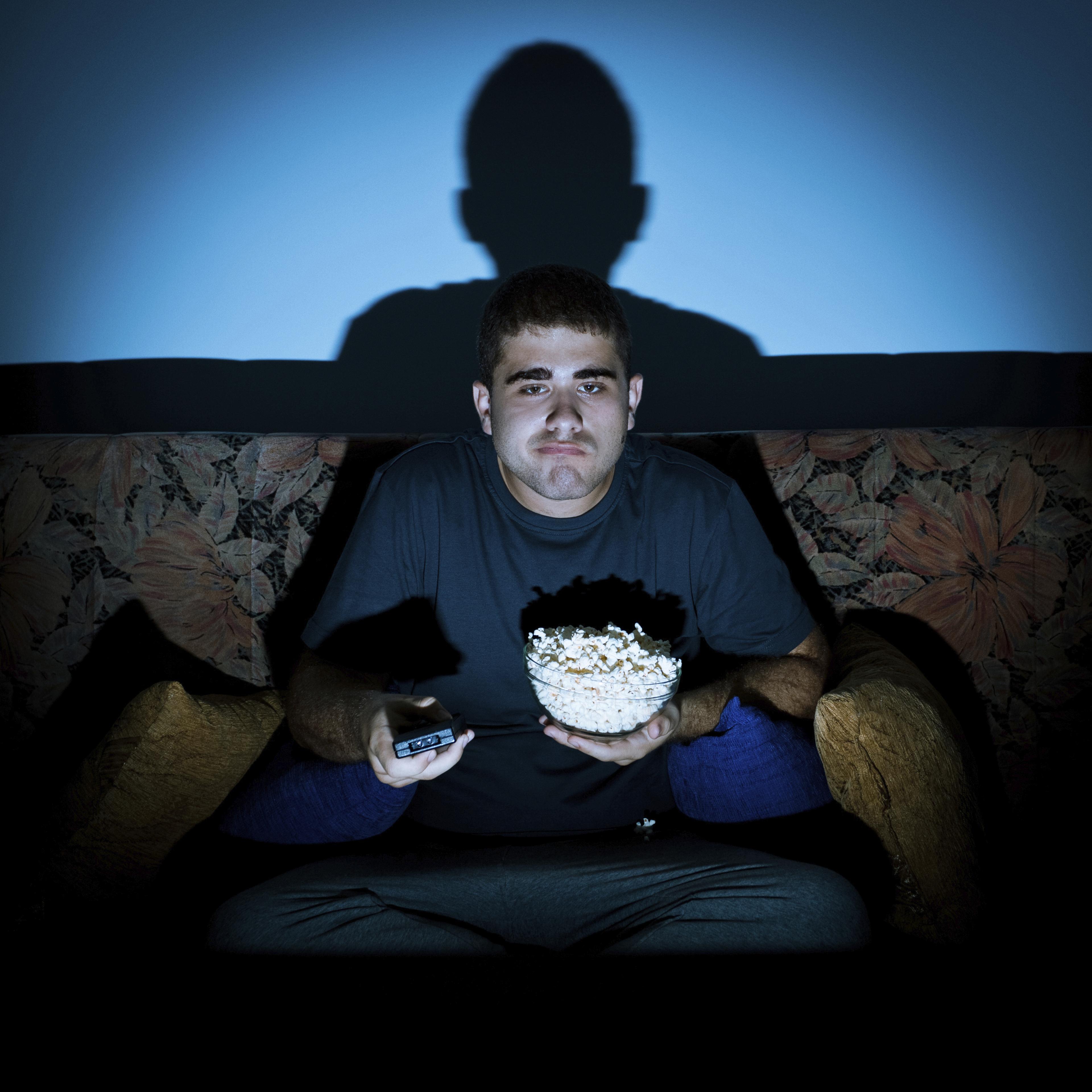 Man watching TV bored and eating
