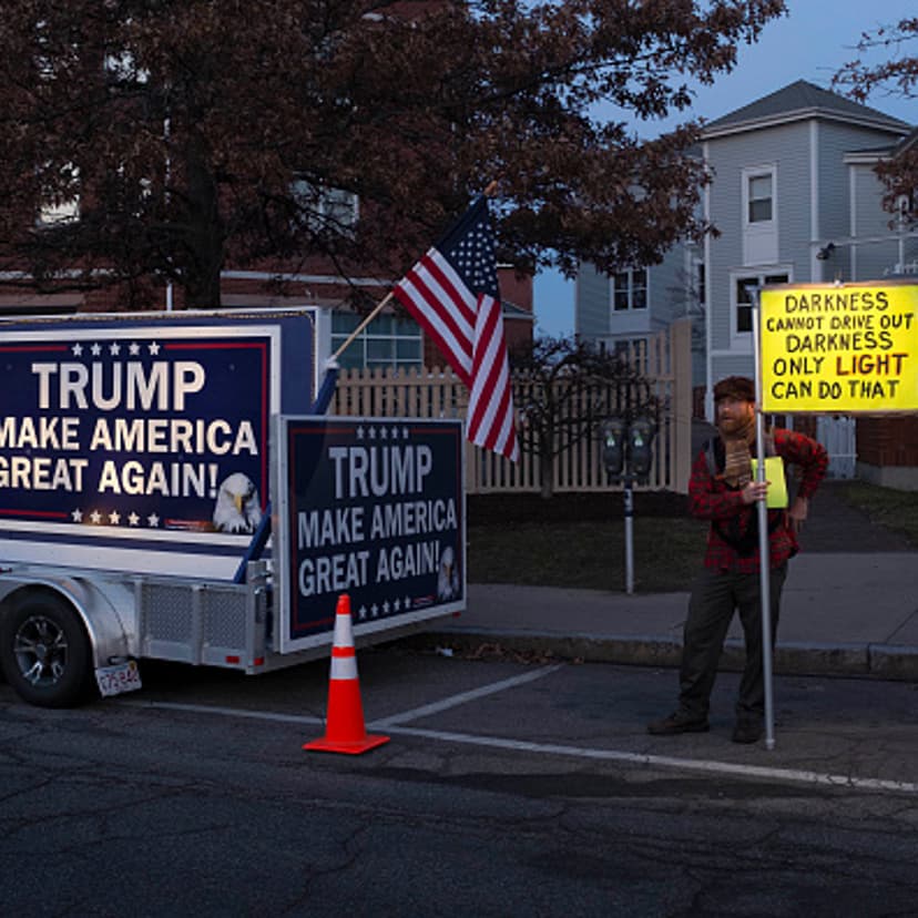 A protester stands beside a pro-Trump billboard outside the Sheraton Portsmouth Harborside Hotel where Republican Presidential candidate Donald Trump is due to speak at the New England Police Benevolent Association Meeting December 10, 2015 in Portsmouth