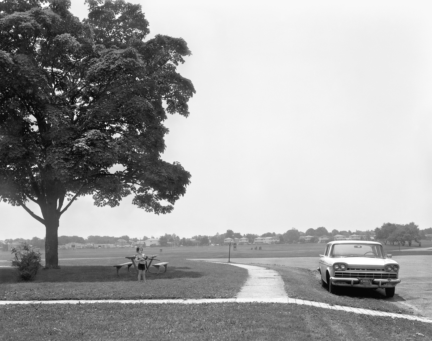 A young boy with a BB gun points toward a car at Miller Field, Staten Island. 
