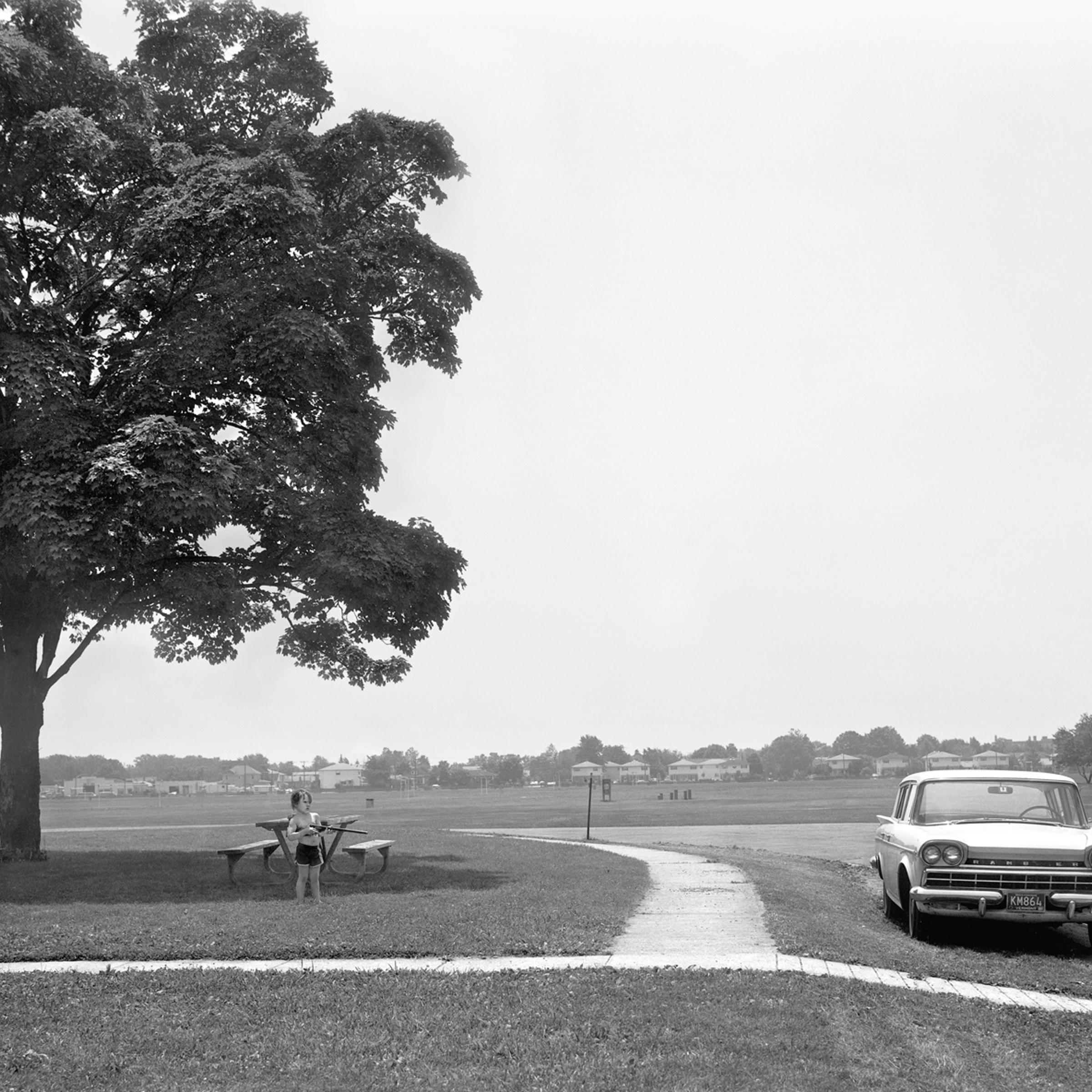 A young boy with a BB gun points toward a car at Miller Field, Staten Island.