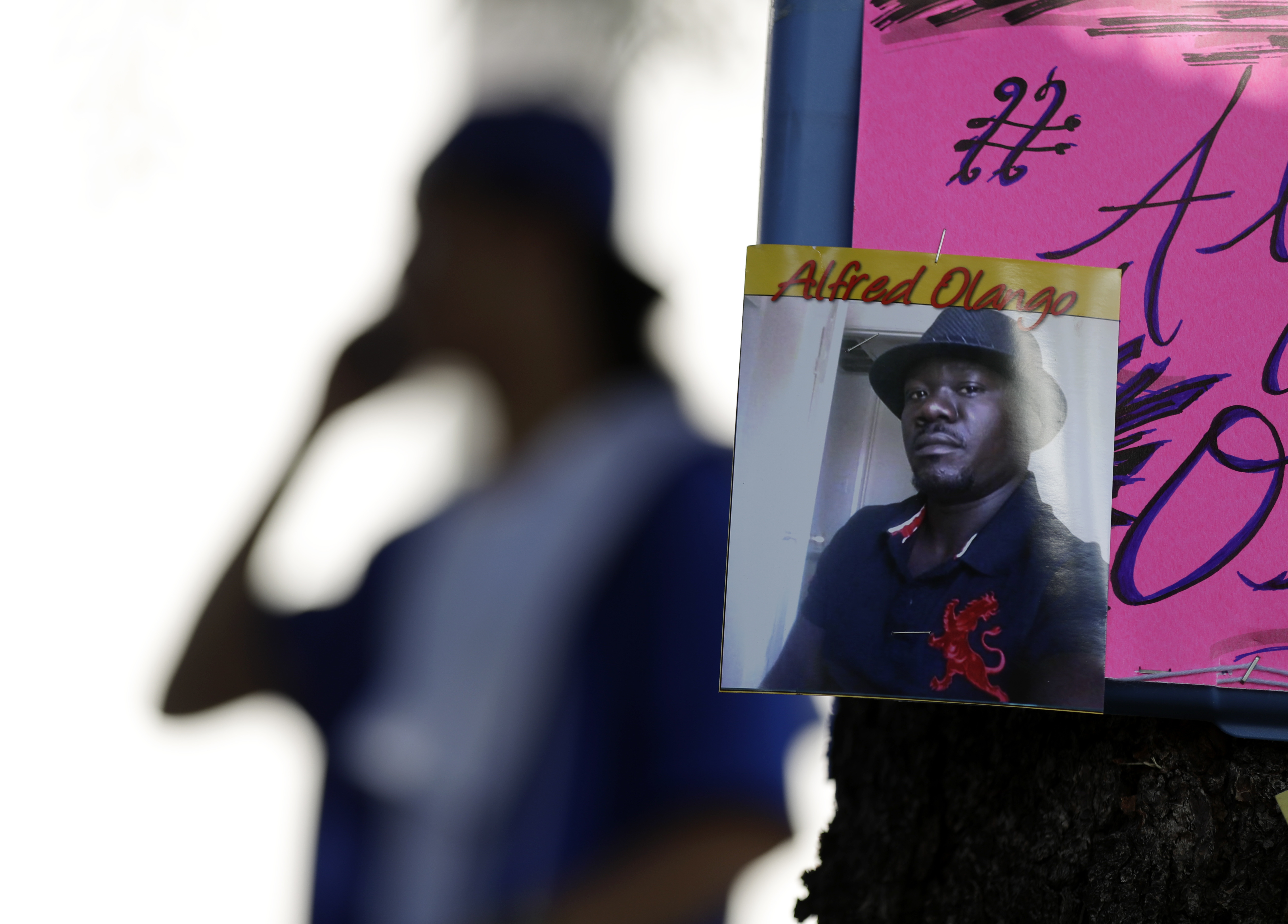 A man stands behind a picture of Alfred Olango during a protest, in El Cajon, Calif., on Sept. 28, 2016.