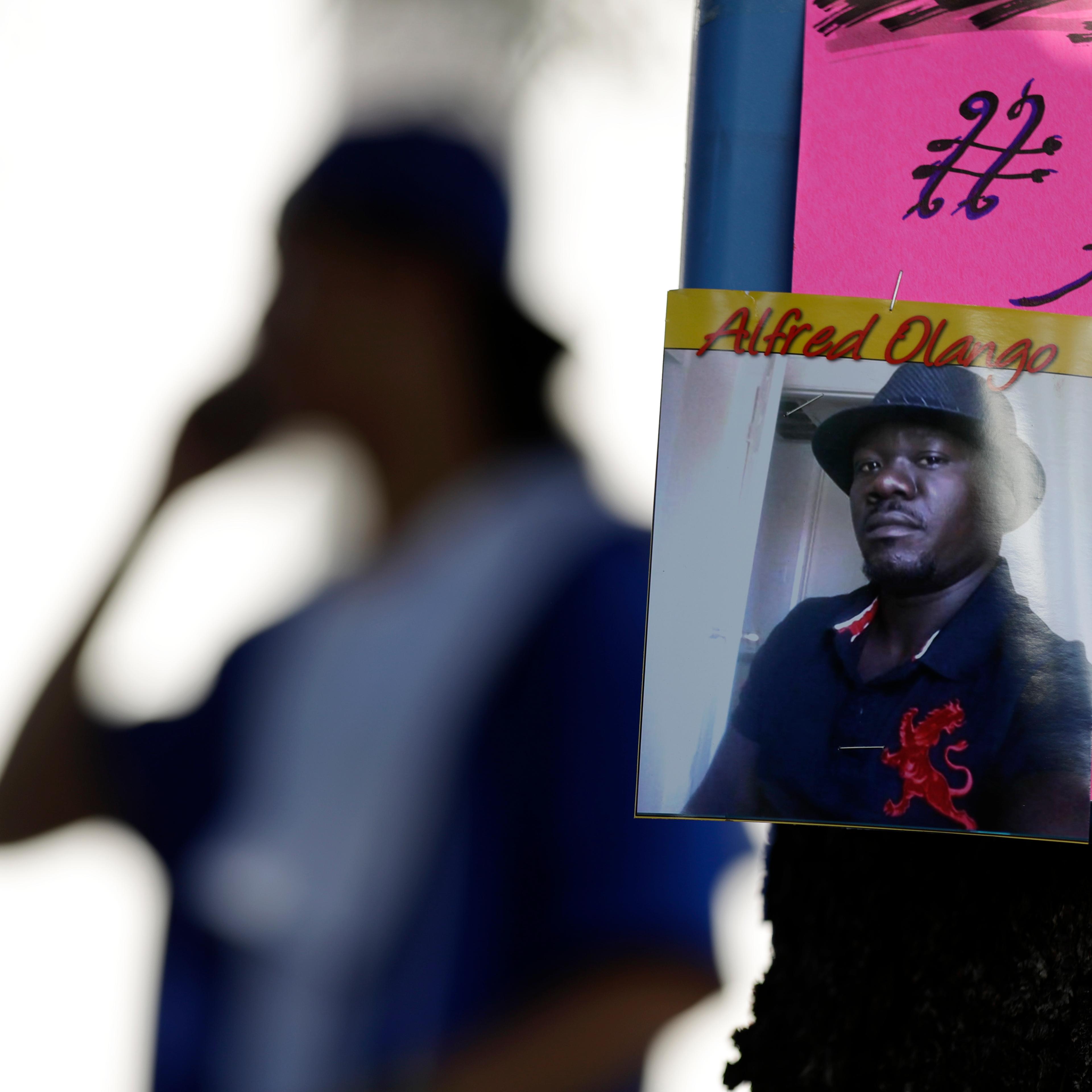 A man stands behind a picture of Alfred Olango during a protest, in El Cajon, Calif., on Sept. 28, 2016.