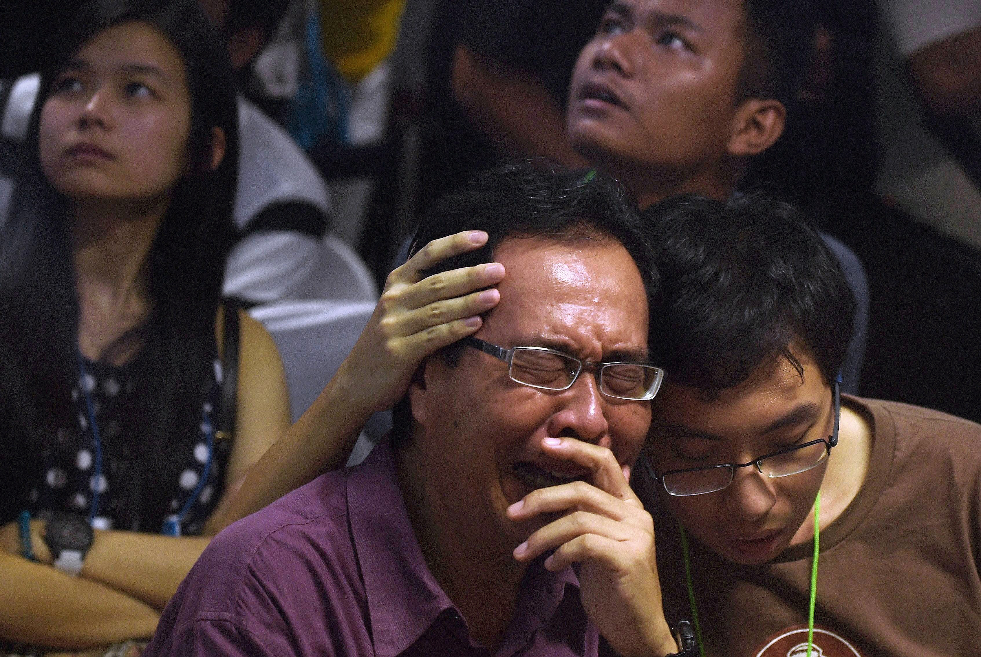 Family members of passengers onboard the missing AirAsia flight QZ8501 react after watching news reports showing an unidentified body floating in the Java sea, inside the crisis-centre set up at Juanda International Airport in Surabaya, Indonesia on Dec.