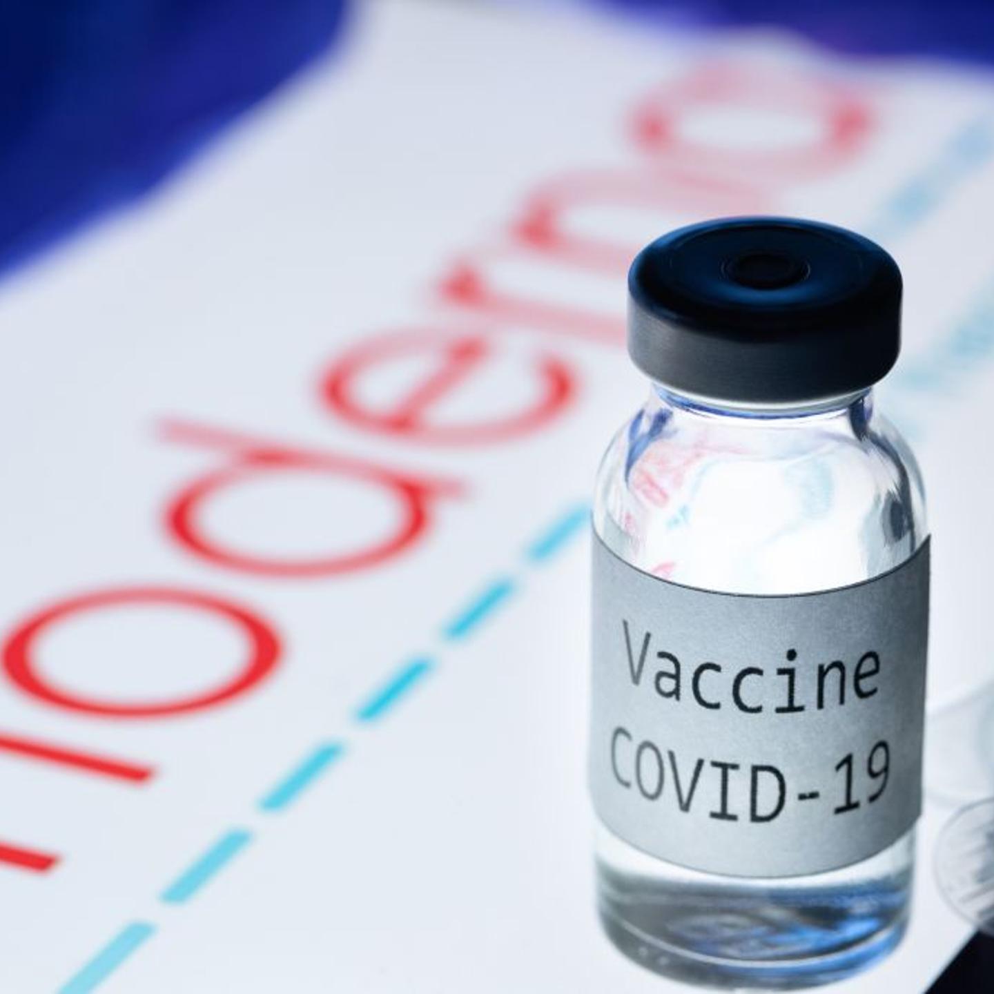 This picture taken on November 18, 2020 shows a syringe and a bottle reading "Vaccine Covid-19" next to the Moderna biotech company logo.