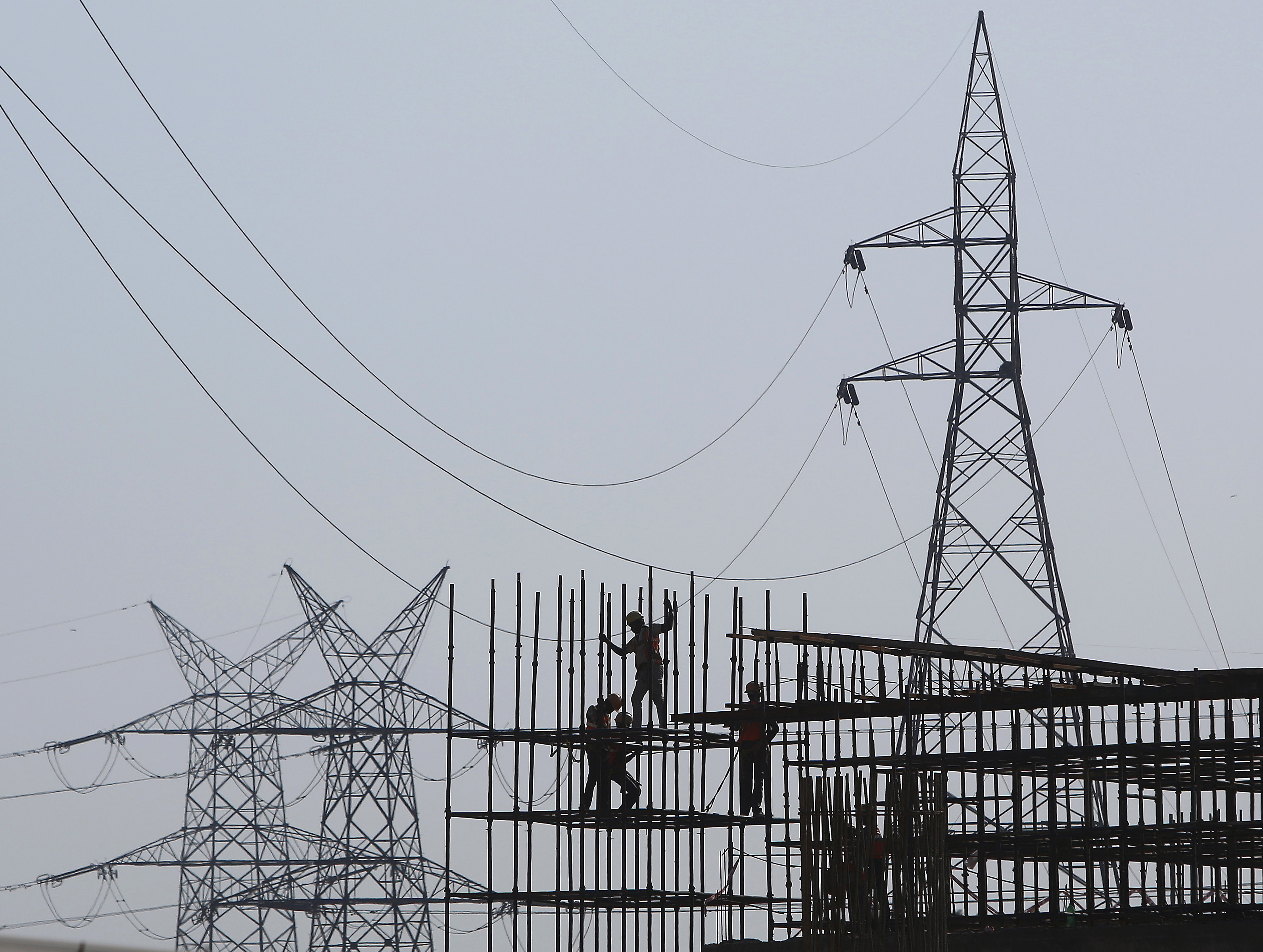 Workers erect scaffolding at the construction site of a metro station in Greater Noida