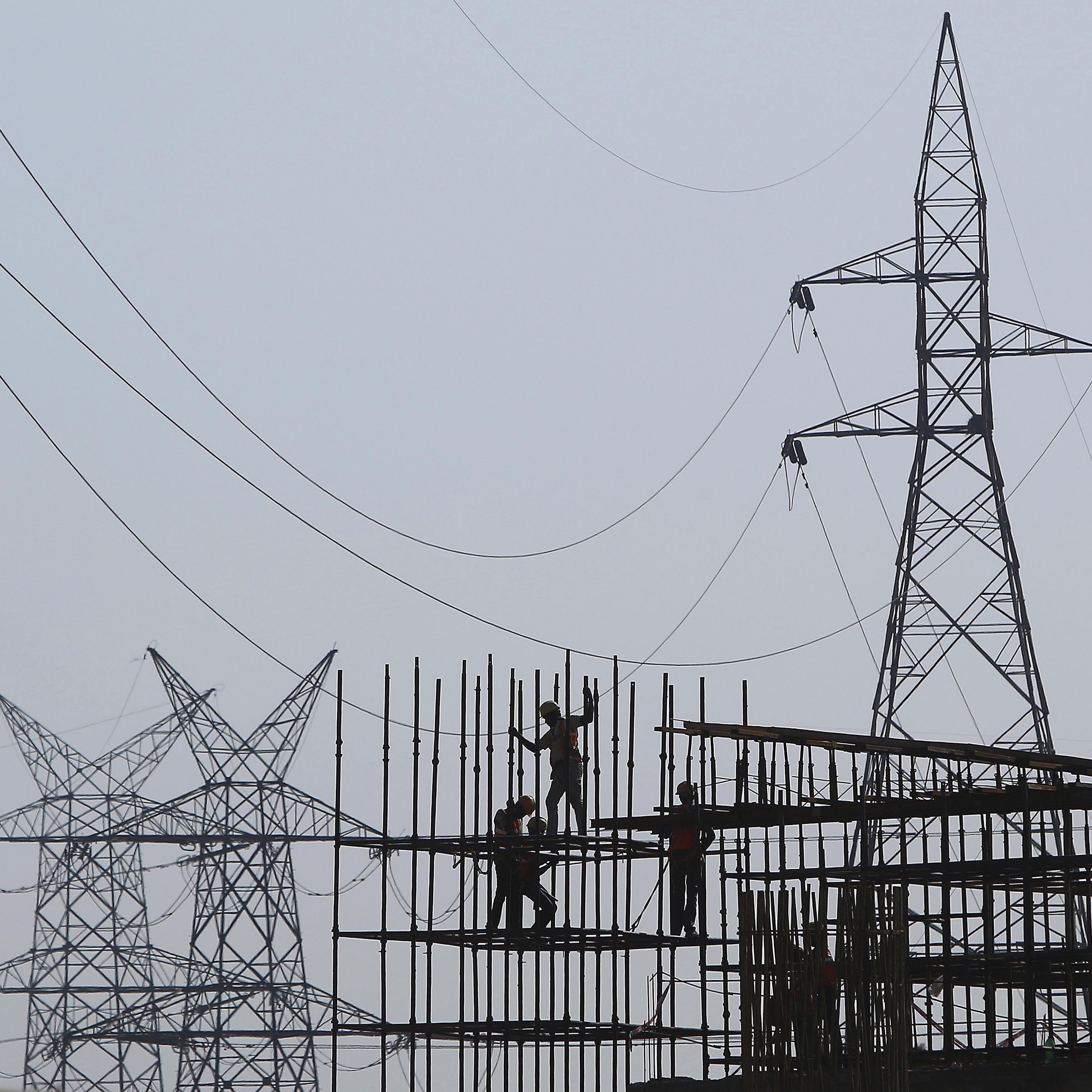 Workers erect scaffolding at the construction site of a metro station in Greater Noida