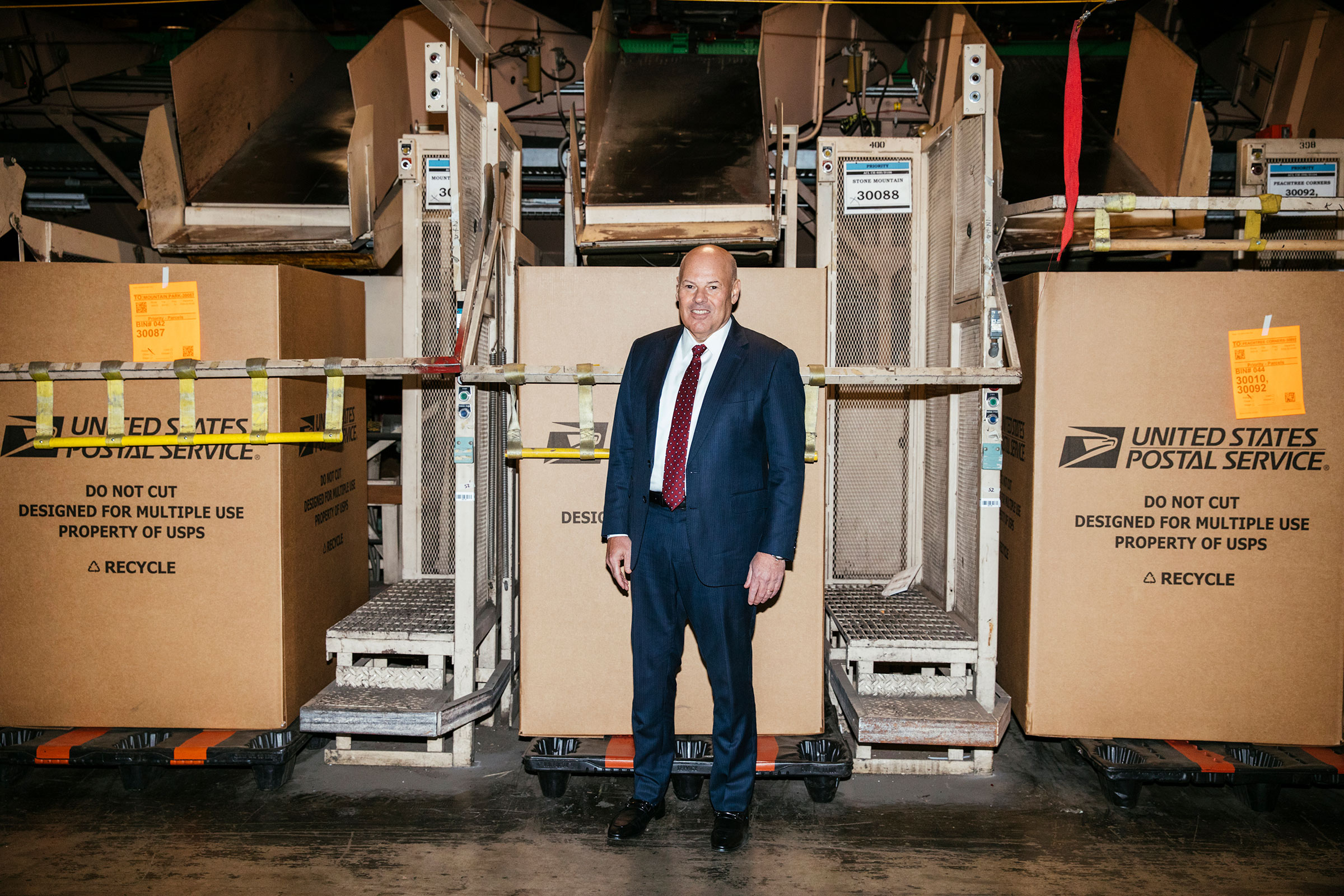United States Postmaster General Louis DeJoy plans to modernize the outdated postal system. He poses for a portrait in front of a parcel sorting machine at the USPS Atlanta Network Distribution Center in Atlanta, Georgia February 3, 2023. Photo by Kendri