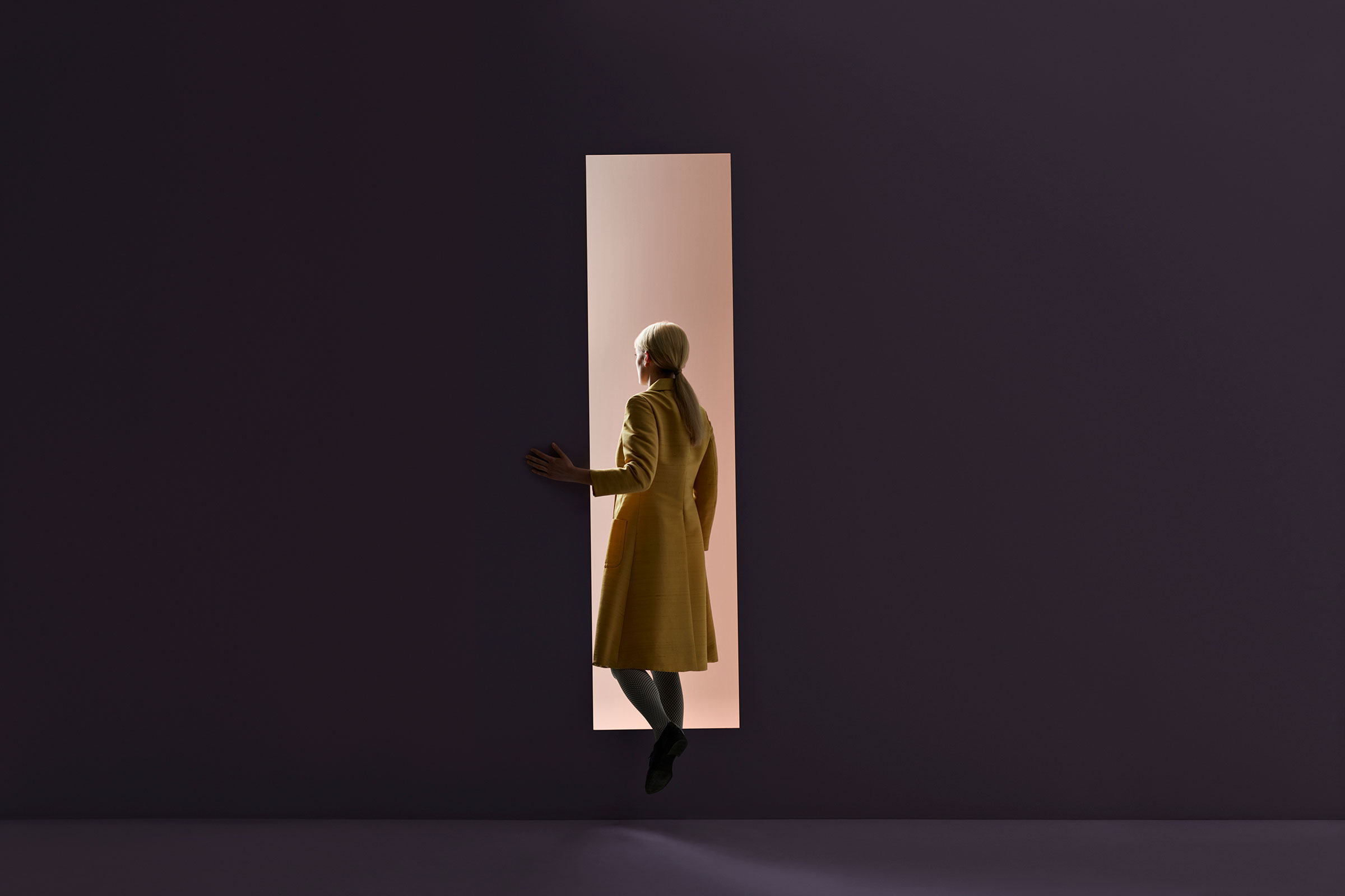Woman walking into rectangular opening in coloured wall