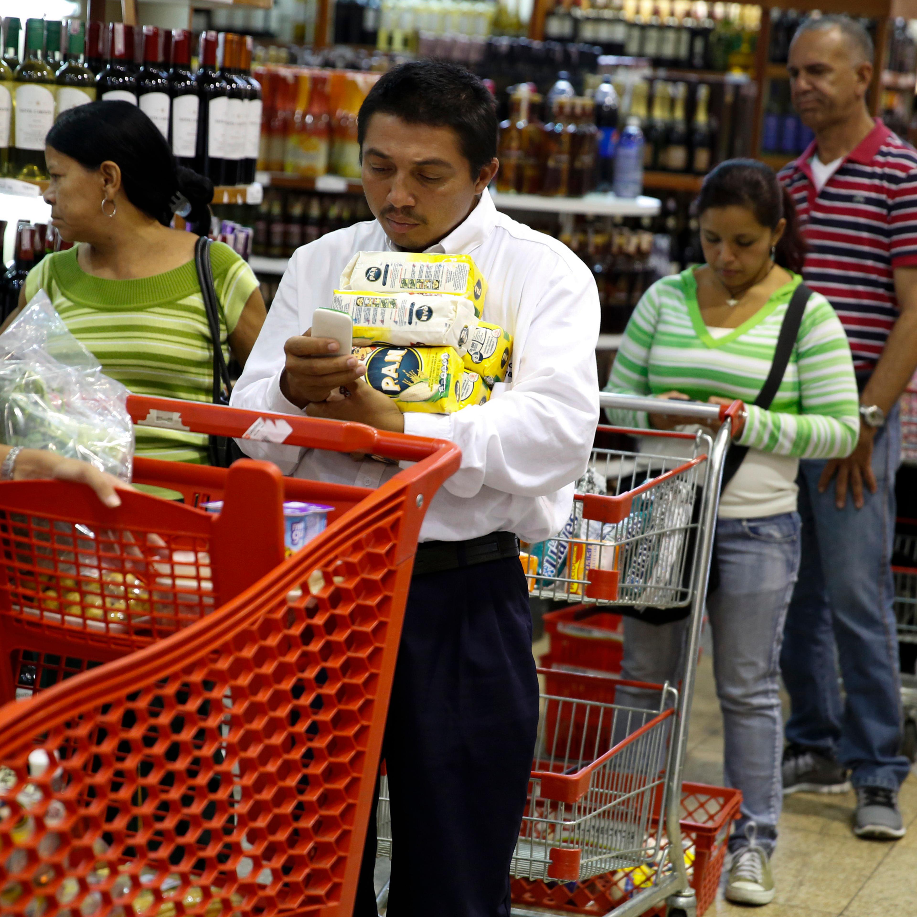 People stand at the checkout line at a supermarket in Caracas