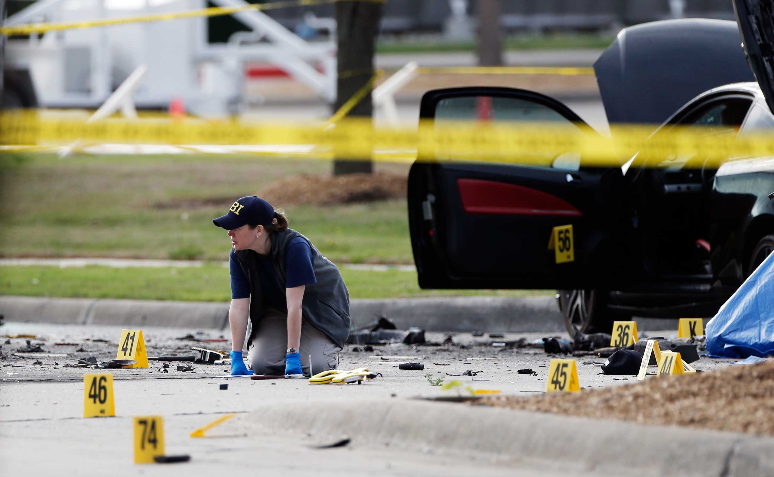 An FBI crime scene investigator documents the area around two deceased gunmen and their vehicle outside the Curtis Culwell Center in Garland, Texas, May 4, 2015.