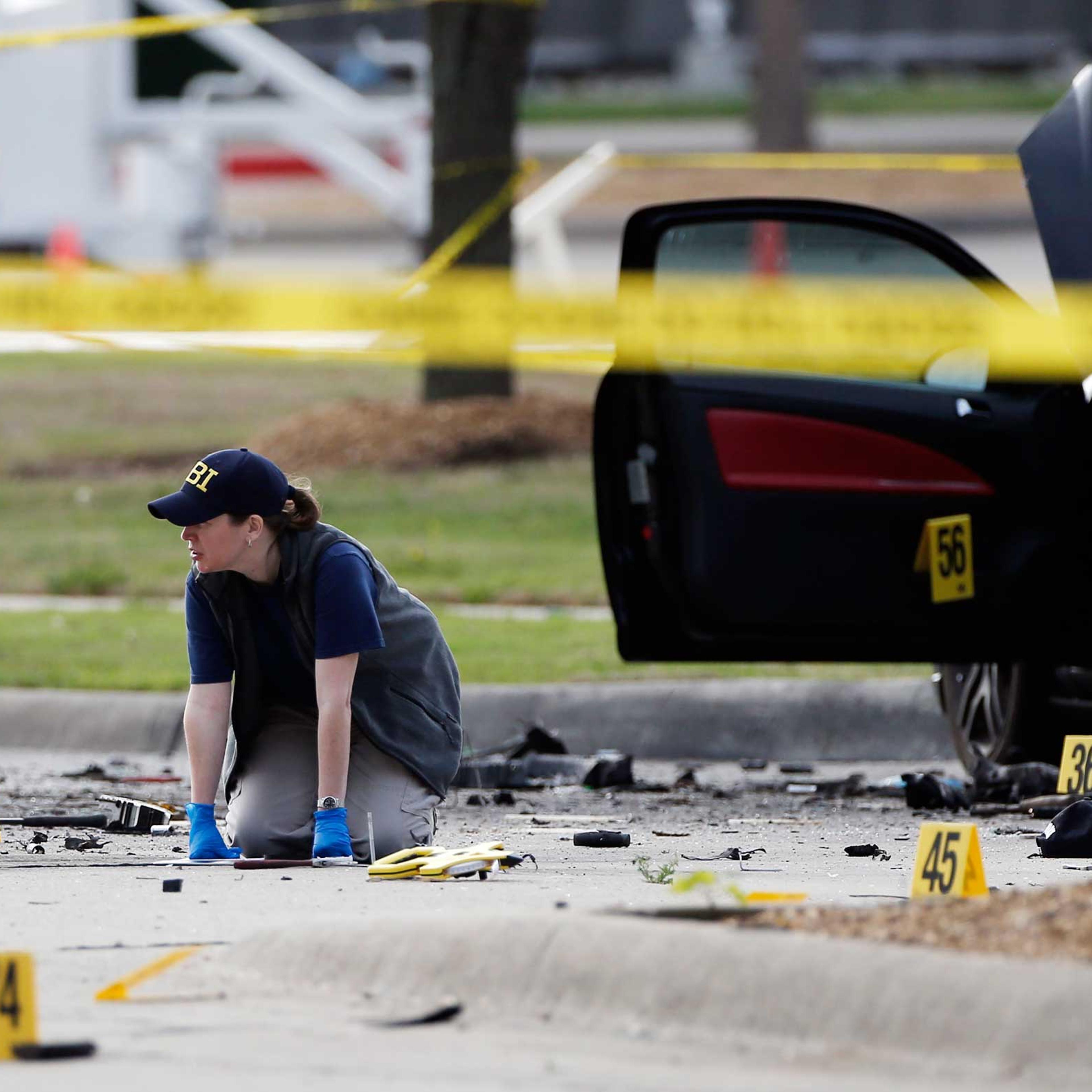 An FBI crime scene investigator documents the area around two deceased gunmen and their vehicle outside the Curtis Culwell Center in Garland, Texas, May 4, 2015.