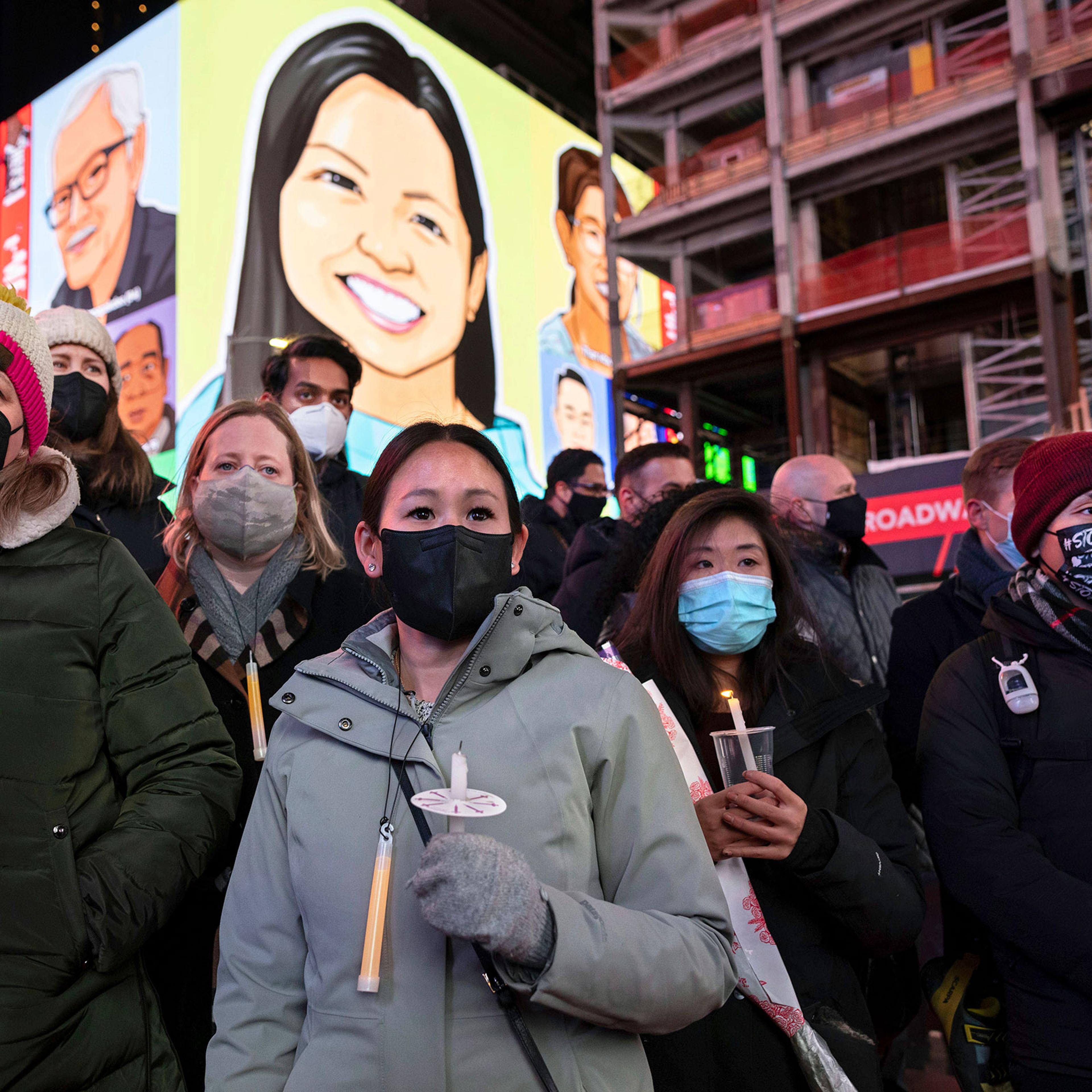 People hold candles during a vigil to honor Michelle Alyssa Go in New York's Times Square, on Jan. 18, 2022.