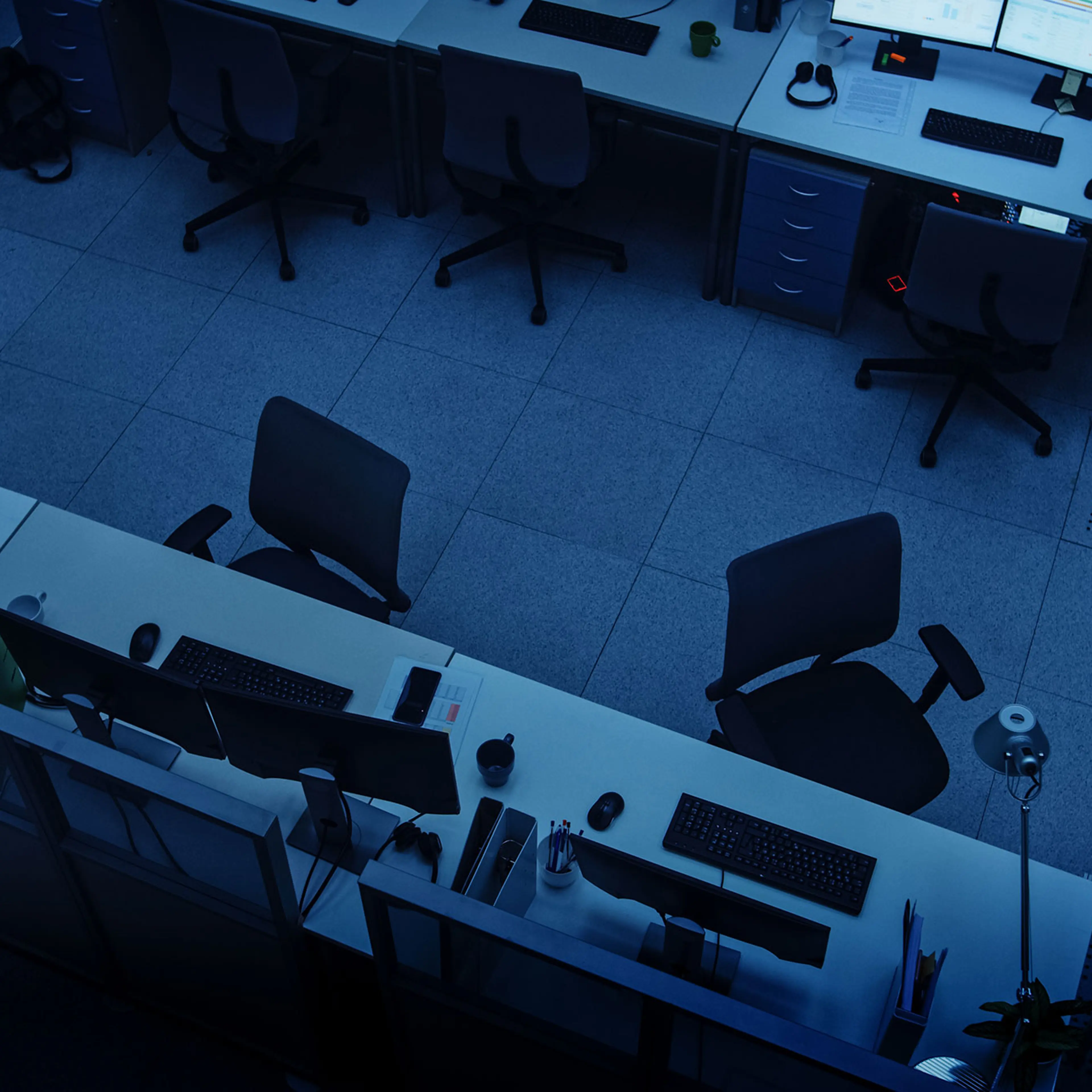 Elevated High Angle Shot of Dark Empty Office with Wheelchairs, Desks and Computers. Concept of Finishing Working Alone Late at Night.