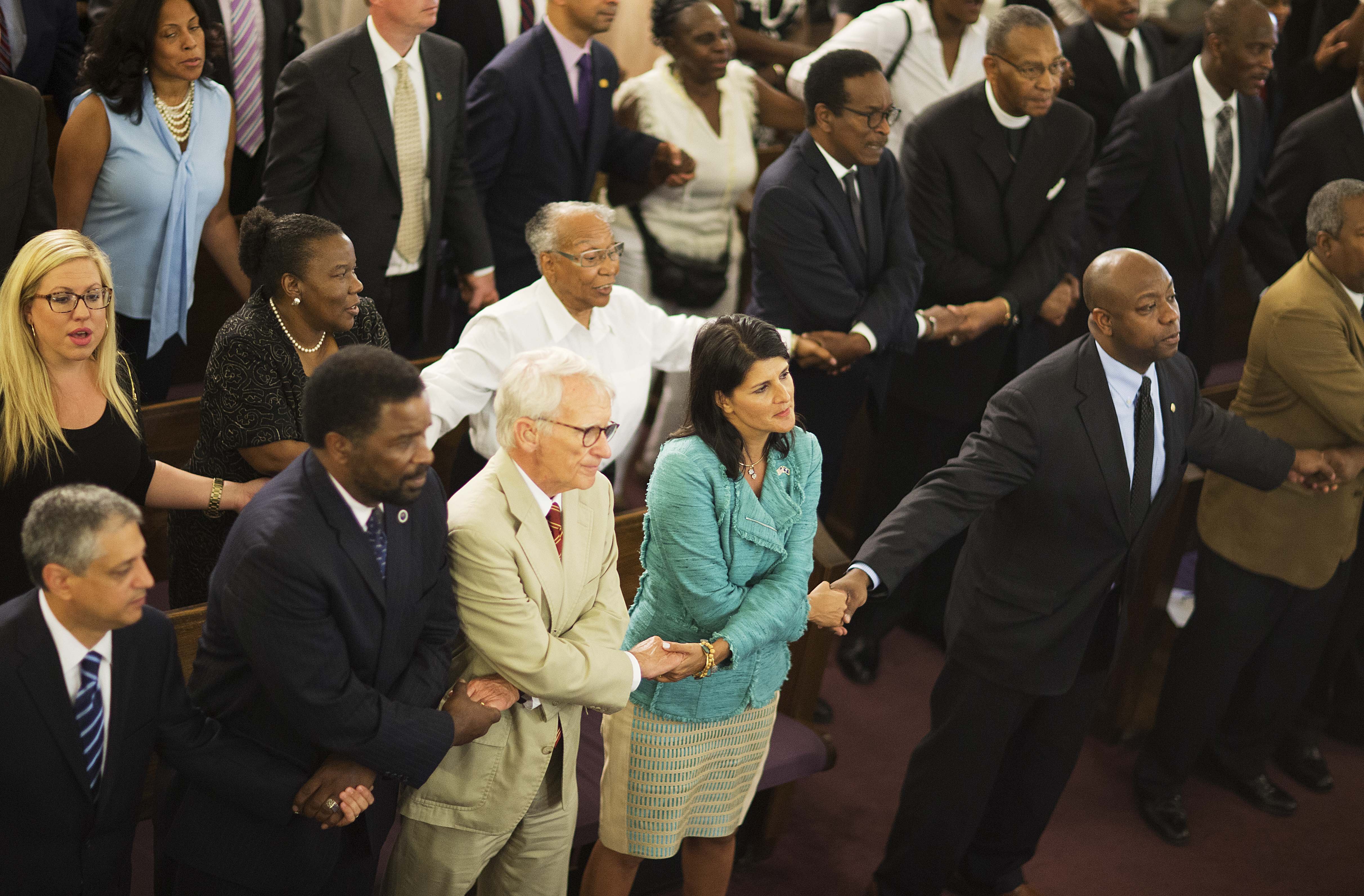 South Carolina Gov. Nikki Haley, center right, joins hands with Charleston Mayor Joseph Riley, left, and Sen. Tim Scott, R-S.C., right, at a memorial service at Morris Brown AME Church for thepeople killed during a prayer meeting inside the historic blac